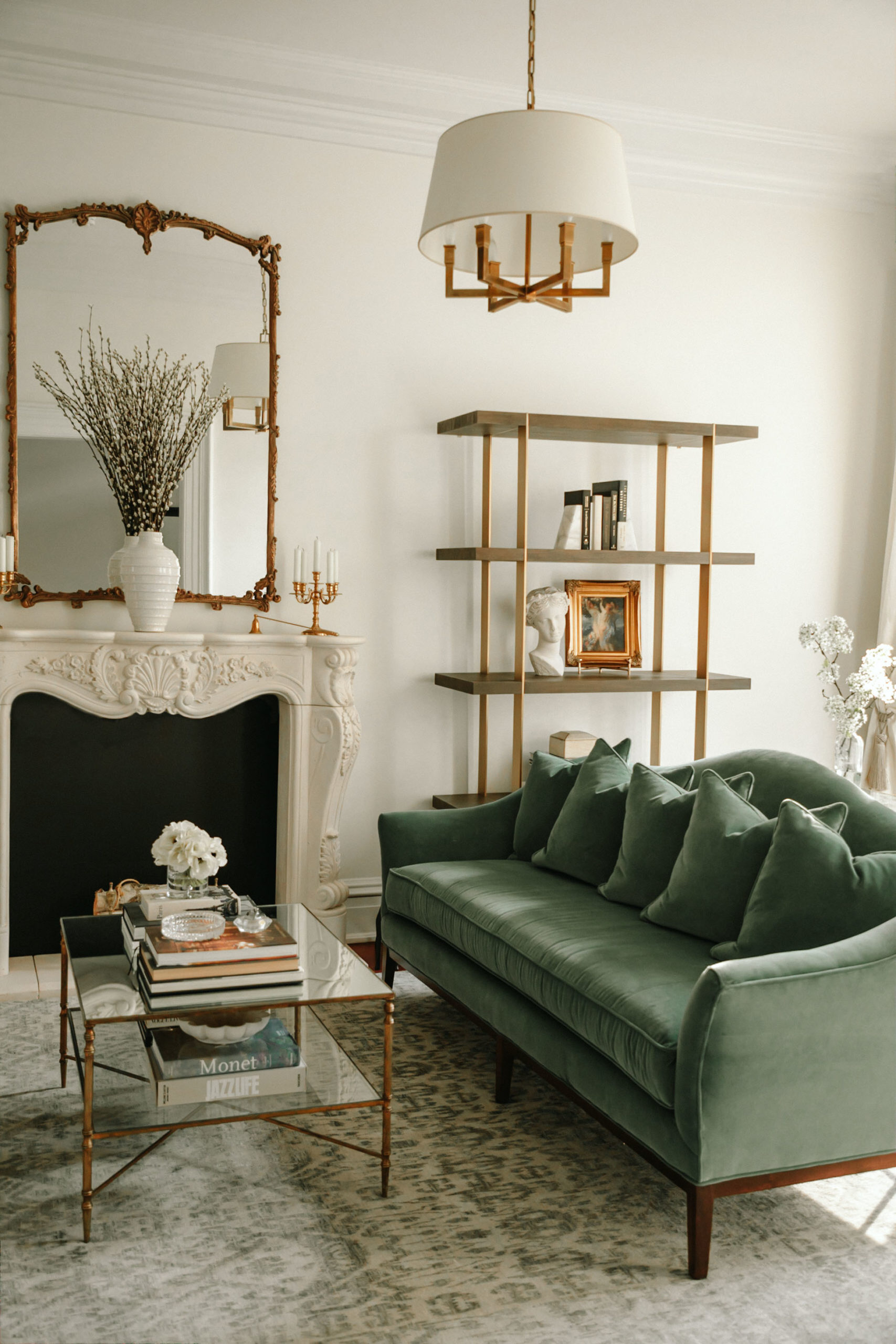 A traditional sitting room with green sofa and glass coffee table on a large area rug.