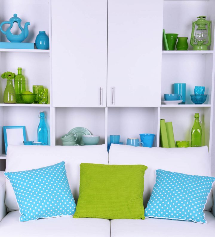 White bookshelf with blue and green accessories that match the living room colors