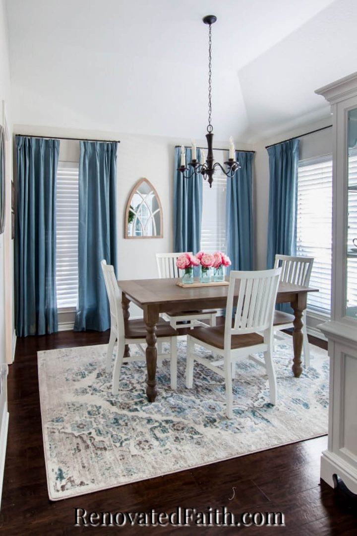 Dining room with blue curtains and walls painted in Sherwin Williams Agreeable Gray (©renovatedfaith.com)