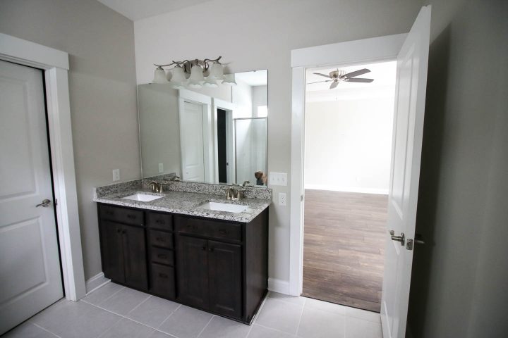 A bathroom with dark cabinets and walls painted in Sherwin Williams Agreeable Gray (©charlestoncrafted.com)
