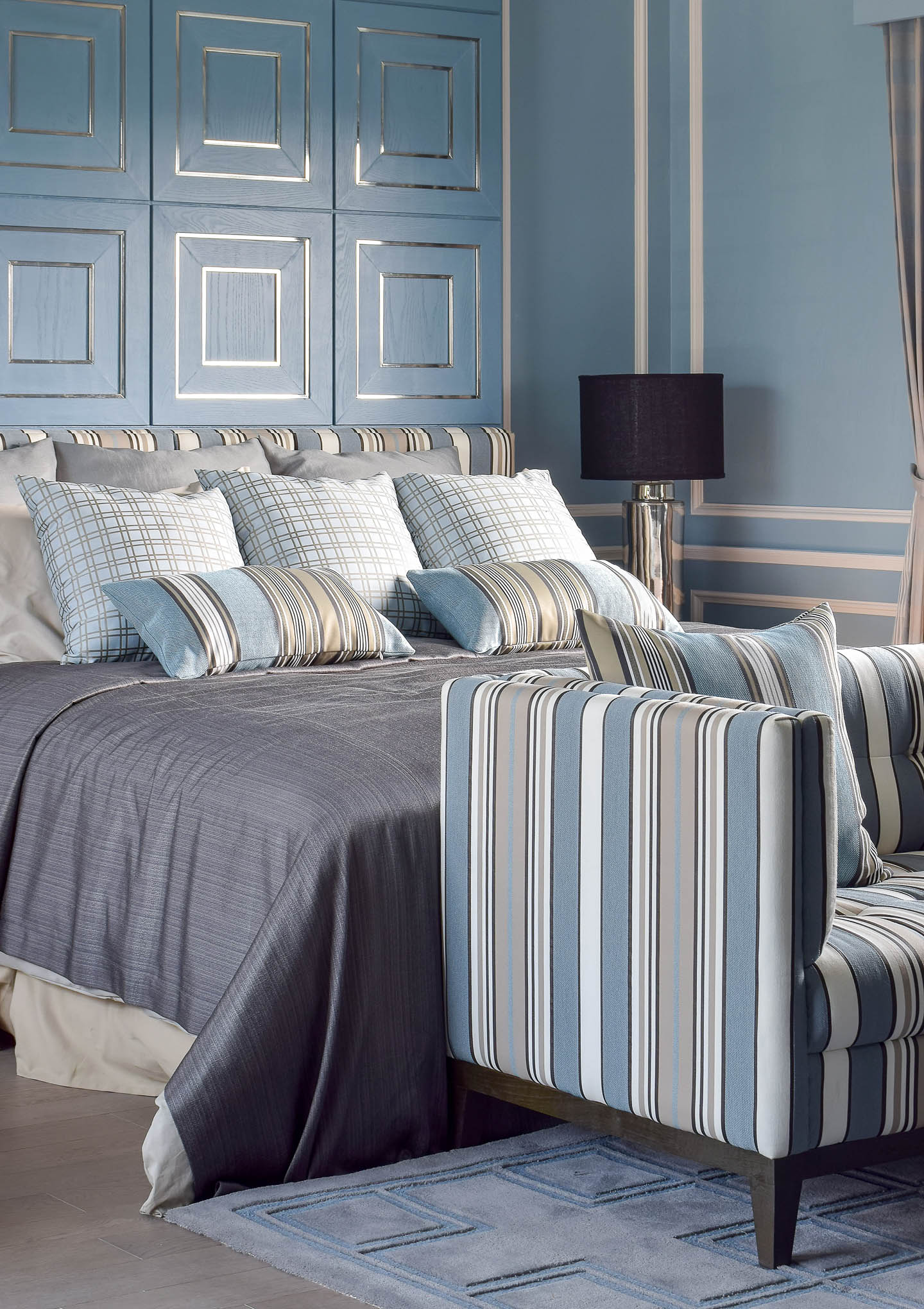 Silver and light blue accent wall behind a bed with gray and blue bedding