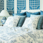 bedroom with blue and white lattice panels on the wall and blue and white toile bedding