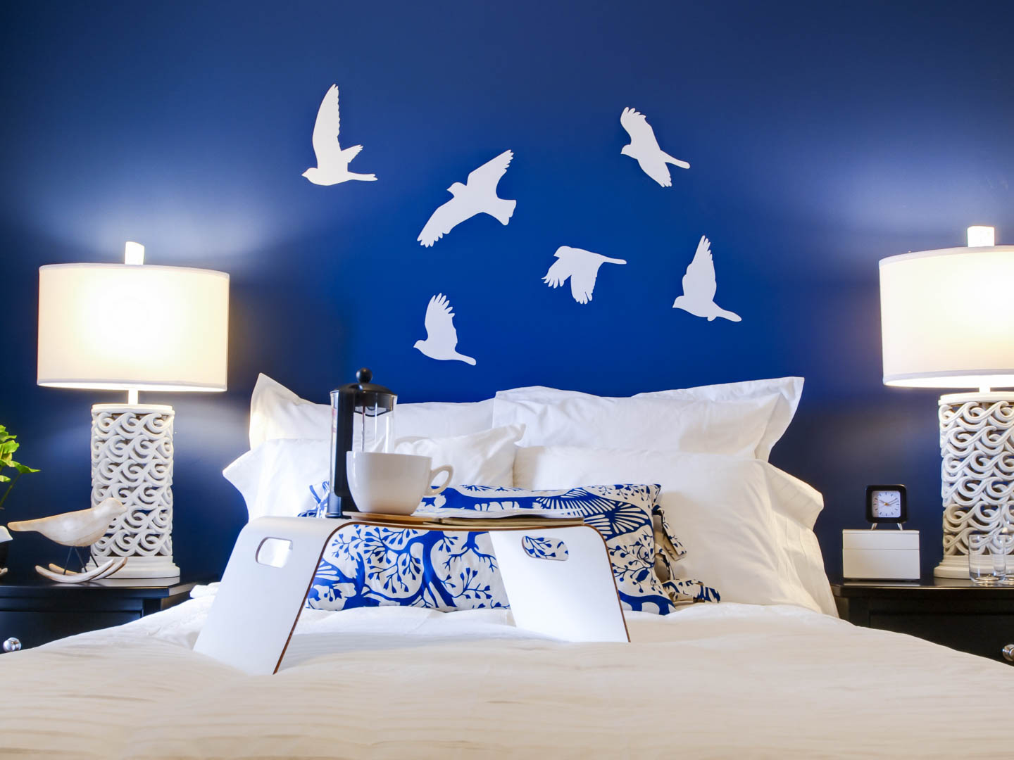 Bedroom with royal blue walls and crisp white bedding and lamps