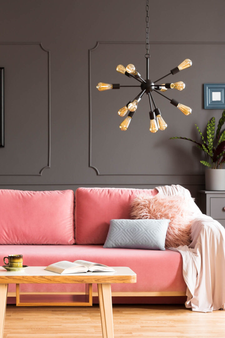A pink sofa with a sputnik light fixture hanging over one side