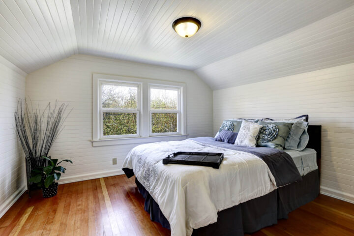 Bedroom with wood paneling that's been painted white