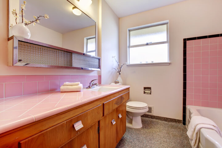 Outdated bathroom interior with pink tile countertop tub