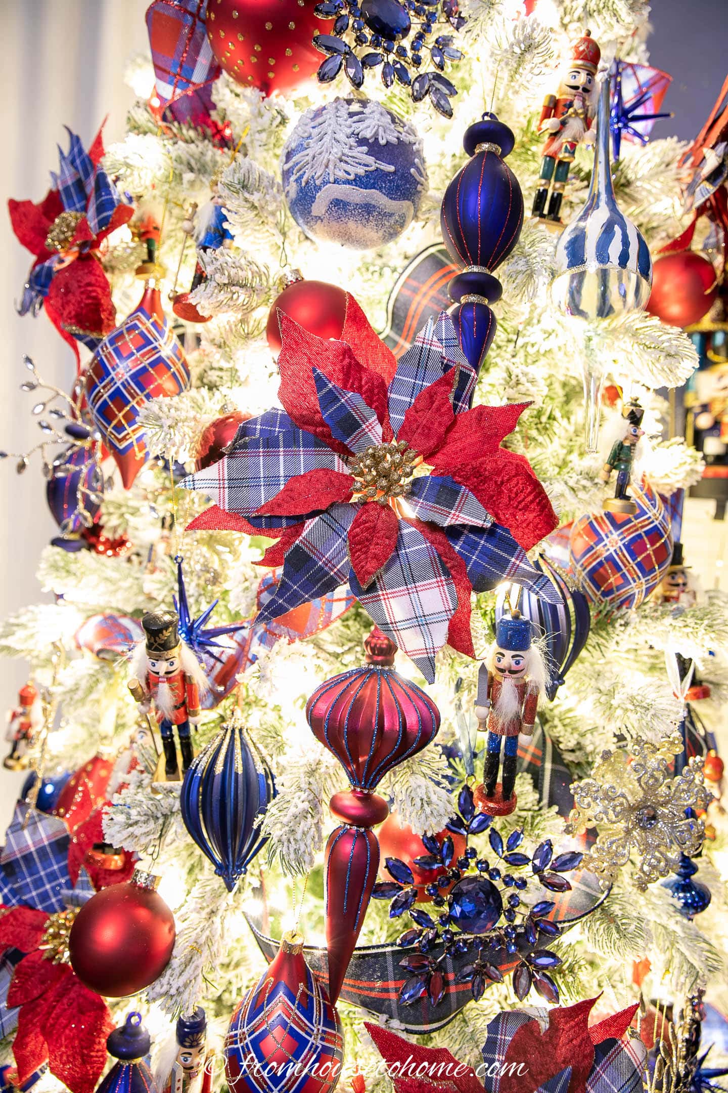 Red and blue plaid poinsettia ornaments on a nutcracker Christmas tree with red and blue ornaments