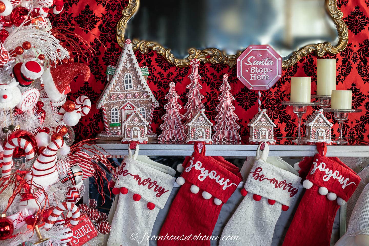 Christmas fireplace mantel decorated with red and white stockings, gingerbread house stocking hangers and red and white trees