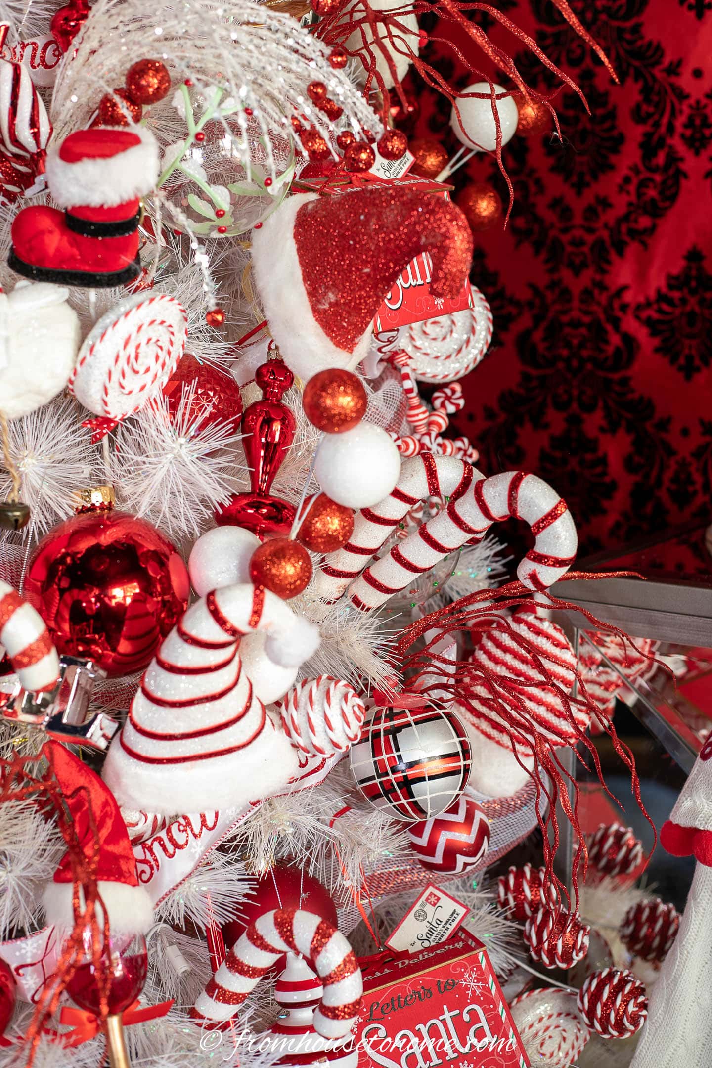 Santa hat, and candy cane picks with other red and white ornaments on a white Christmas tree