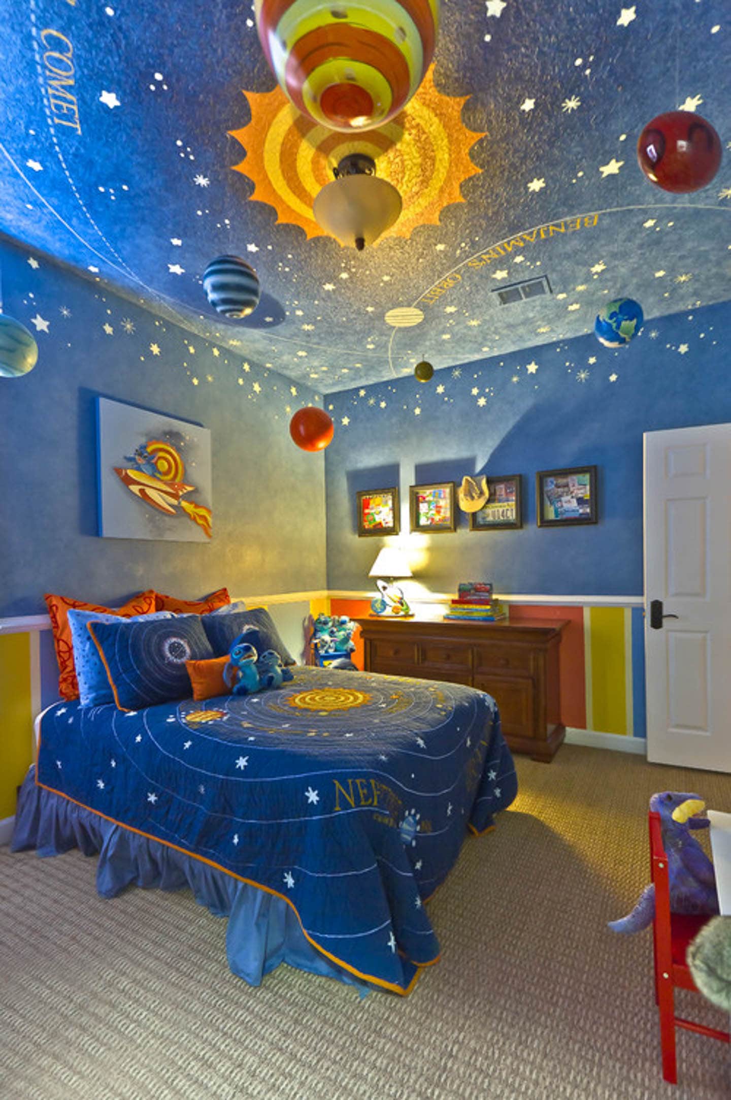 Child's room with blue ceiling and walls painted with the solar system