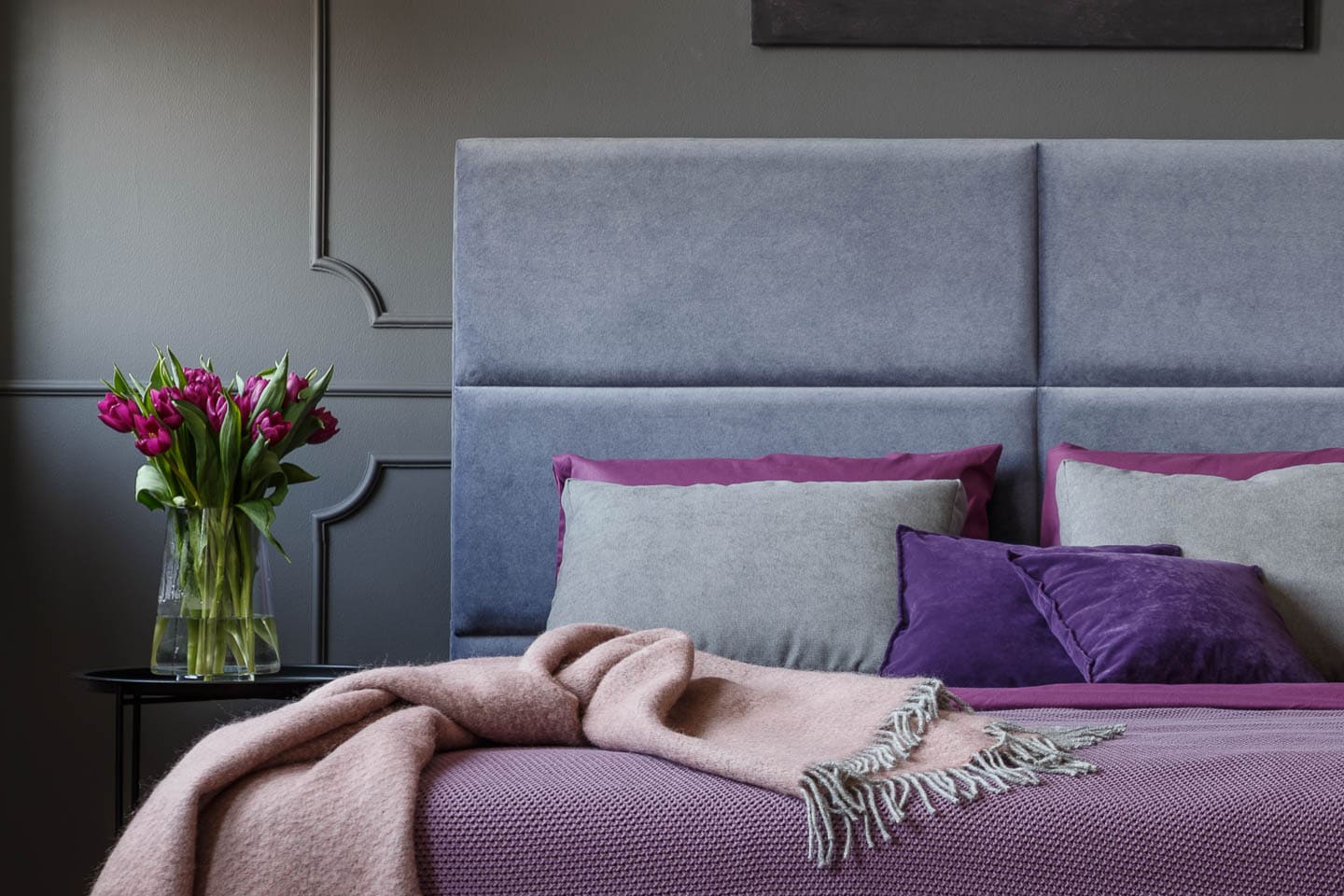light purple and grey bed in front of a grey wall