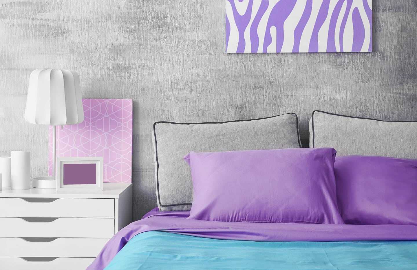 a teal and purple bed in front of a gray wall