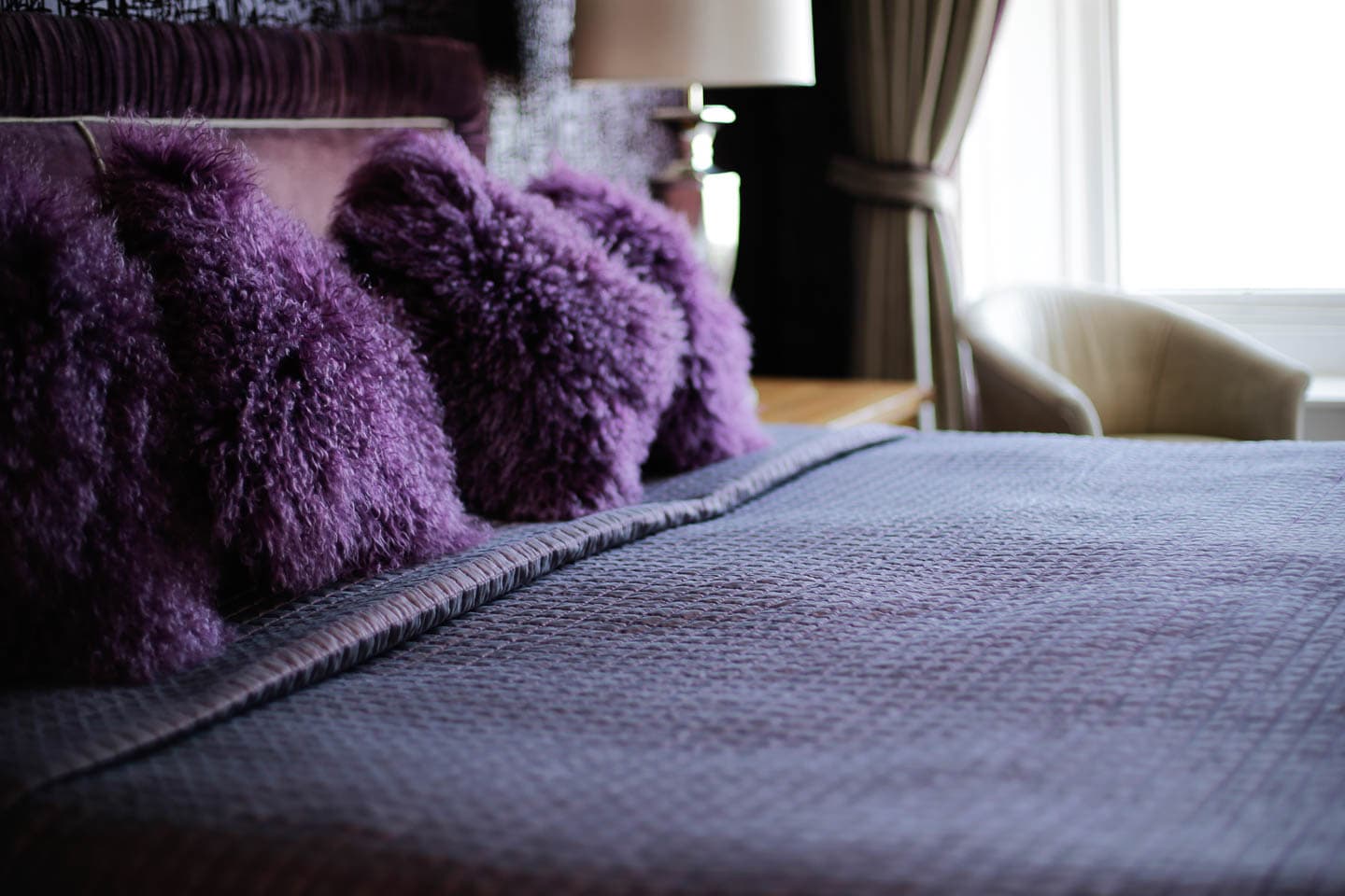 dark purple pillows and blanket on a bed