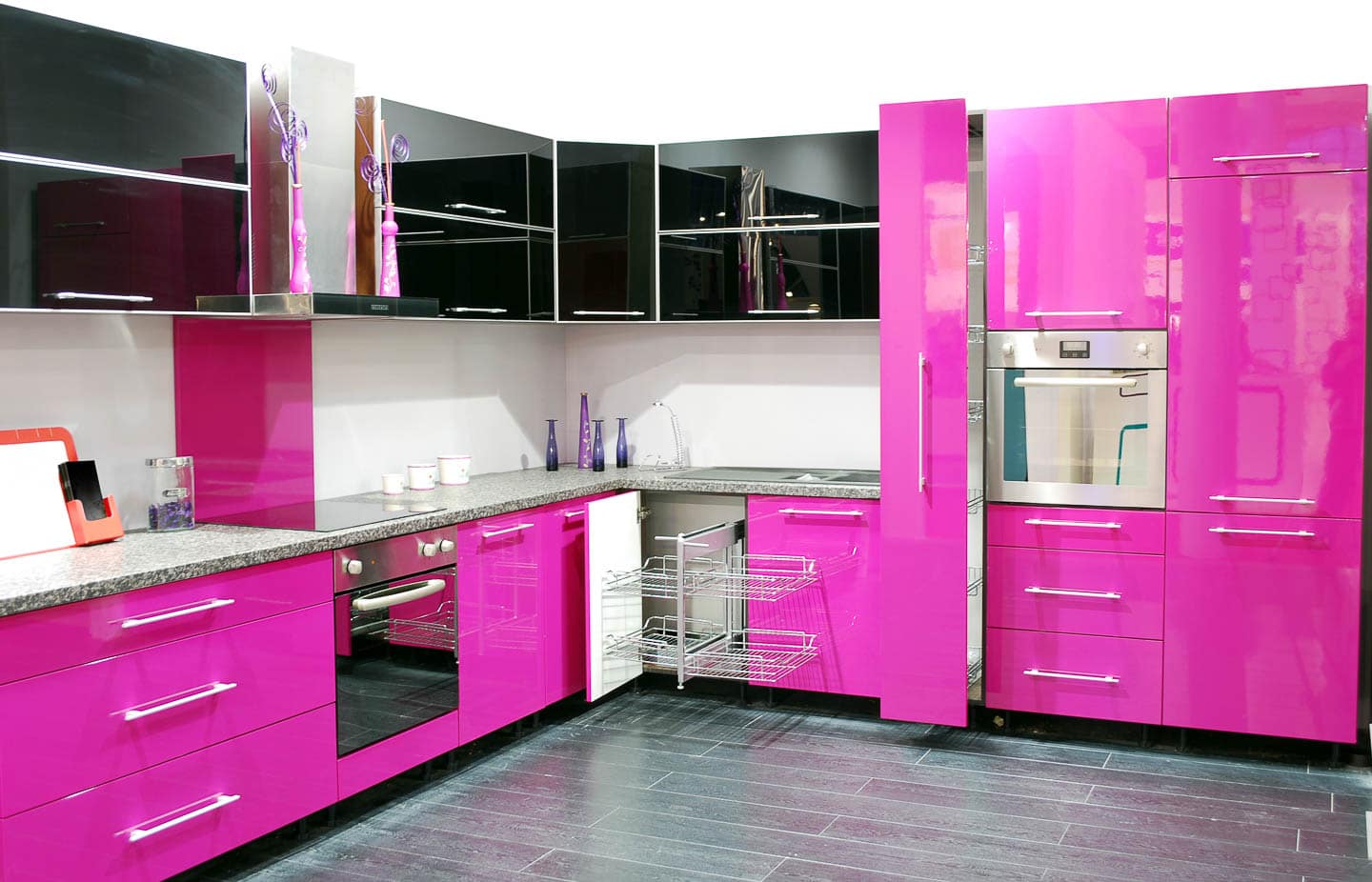 Black and bright pink kitchen cabinets with gray floors and a white backsplash