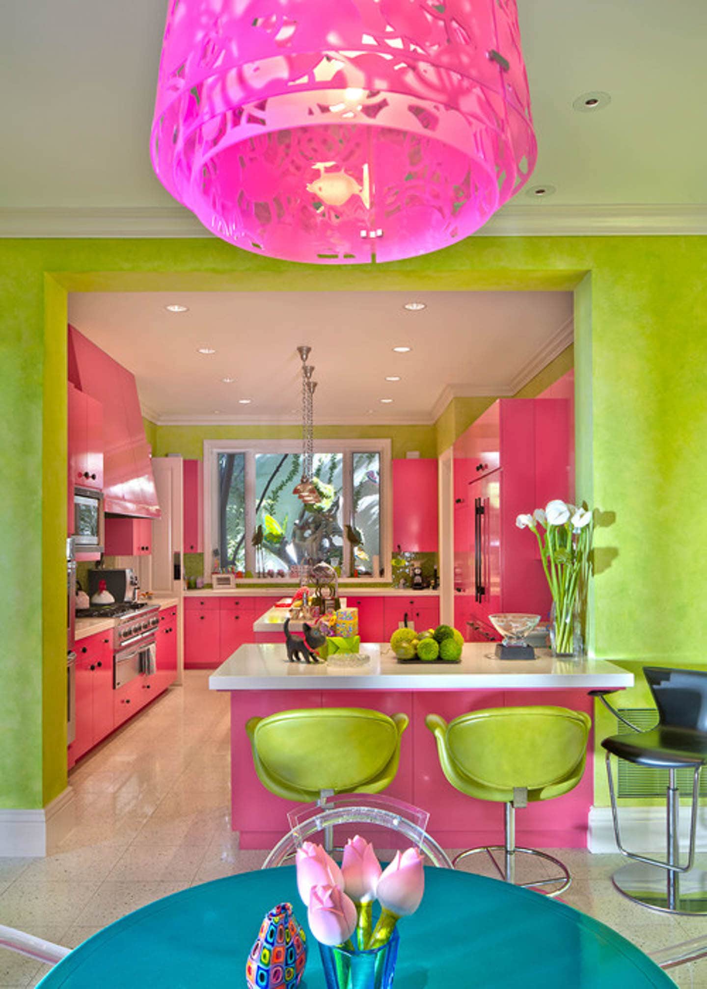 Colorful kitchen with pink kitchen cabinets, white countertops and lime green walls and bar stools