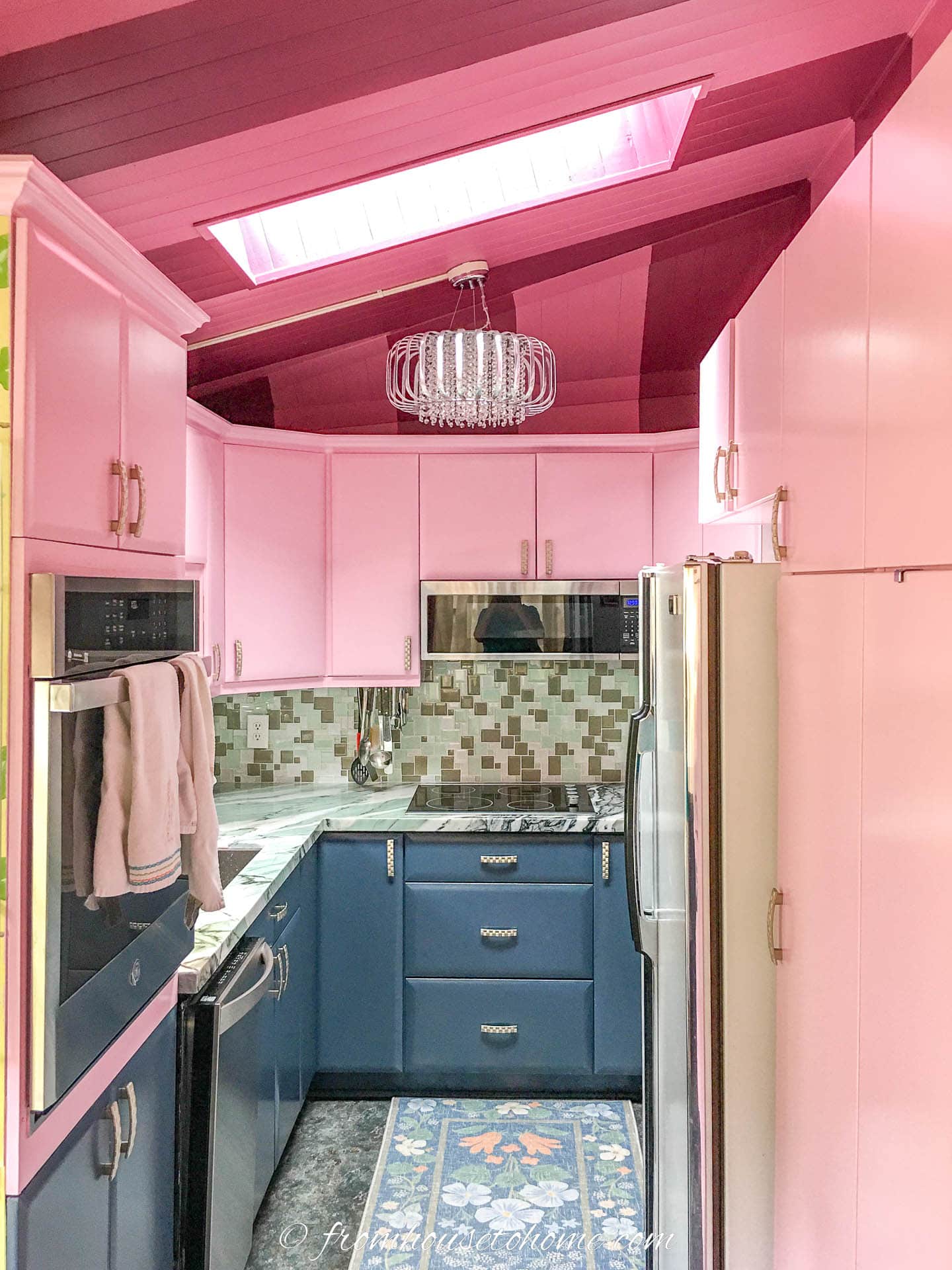 Kitchen with two-toned pink ceiling, pink upper cabinets, light teal backsplash and countertop, and dark teal lower cabinets and floor