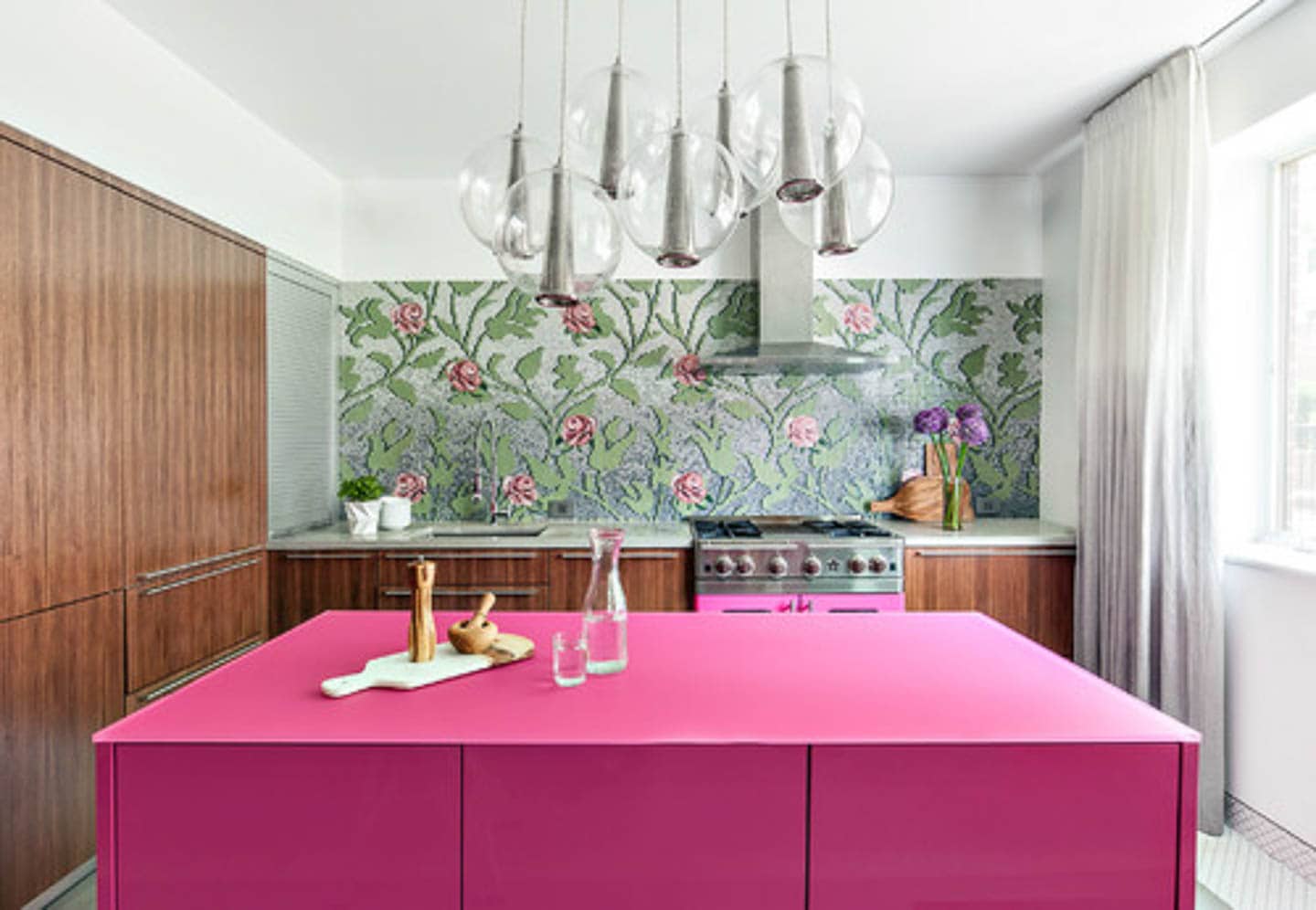 Kitchen with a floral motif glass backsplash, pink kitchen island and stove, and wood cabinets