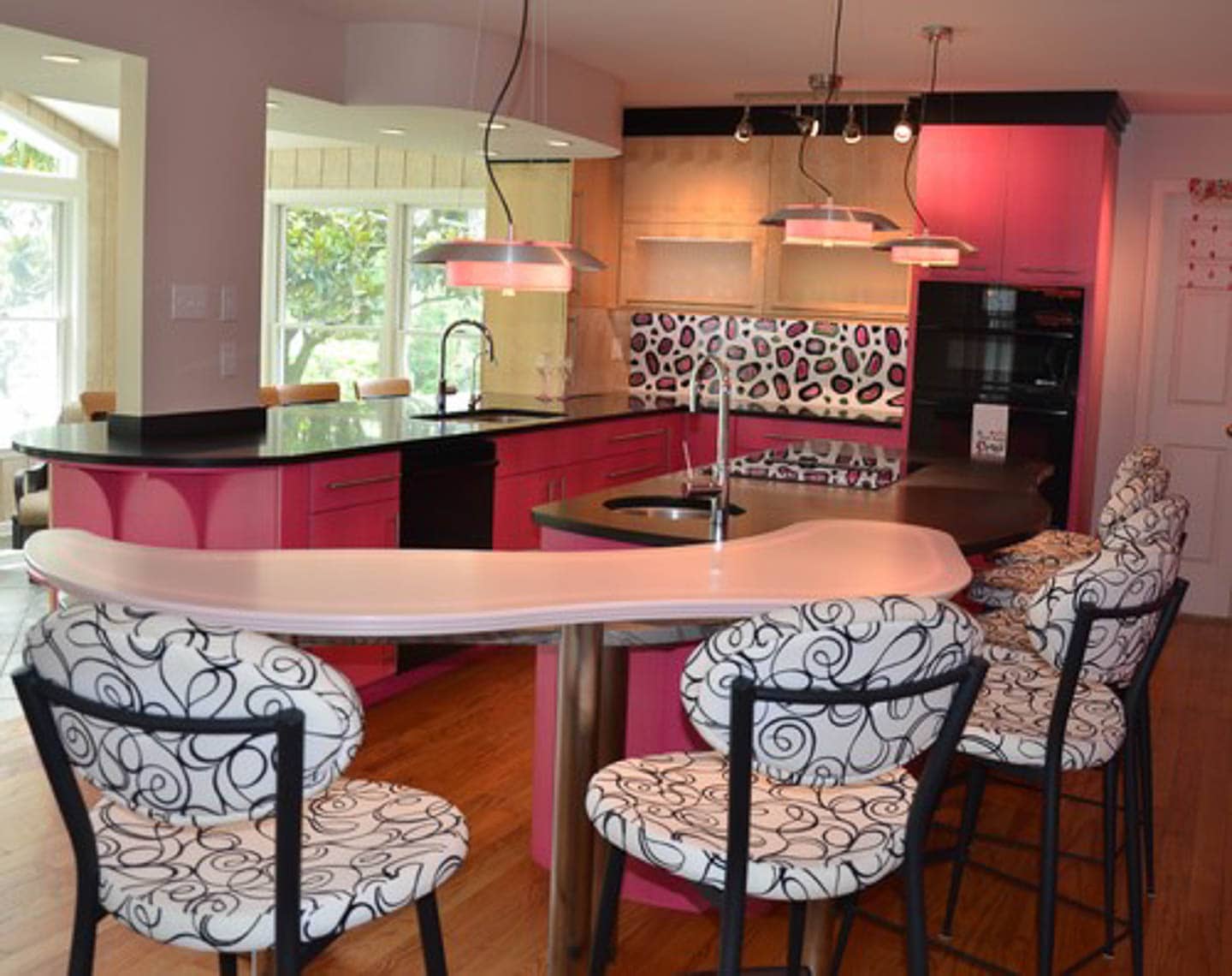 Eclectic kitchen with pink cabinets, black countertops and a white, pink and black leopard print backsplash