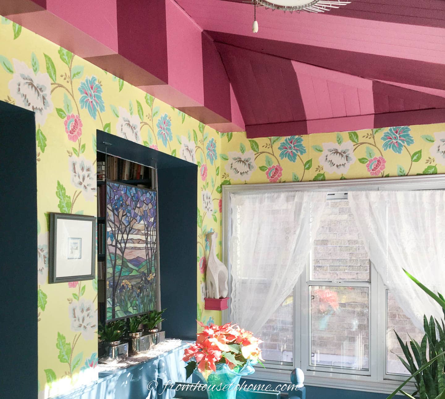 walls covered in yellow, blue and pink floral wallpaper and a pink striped ceiling