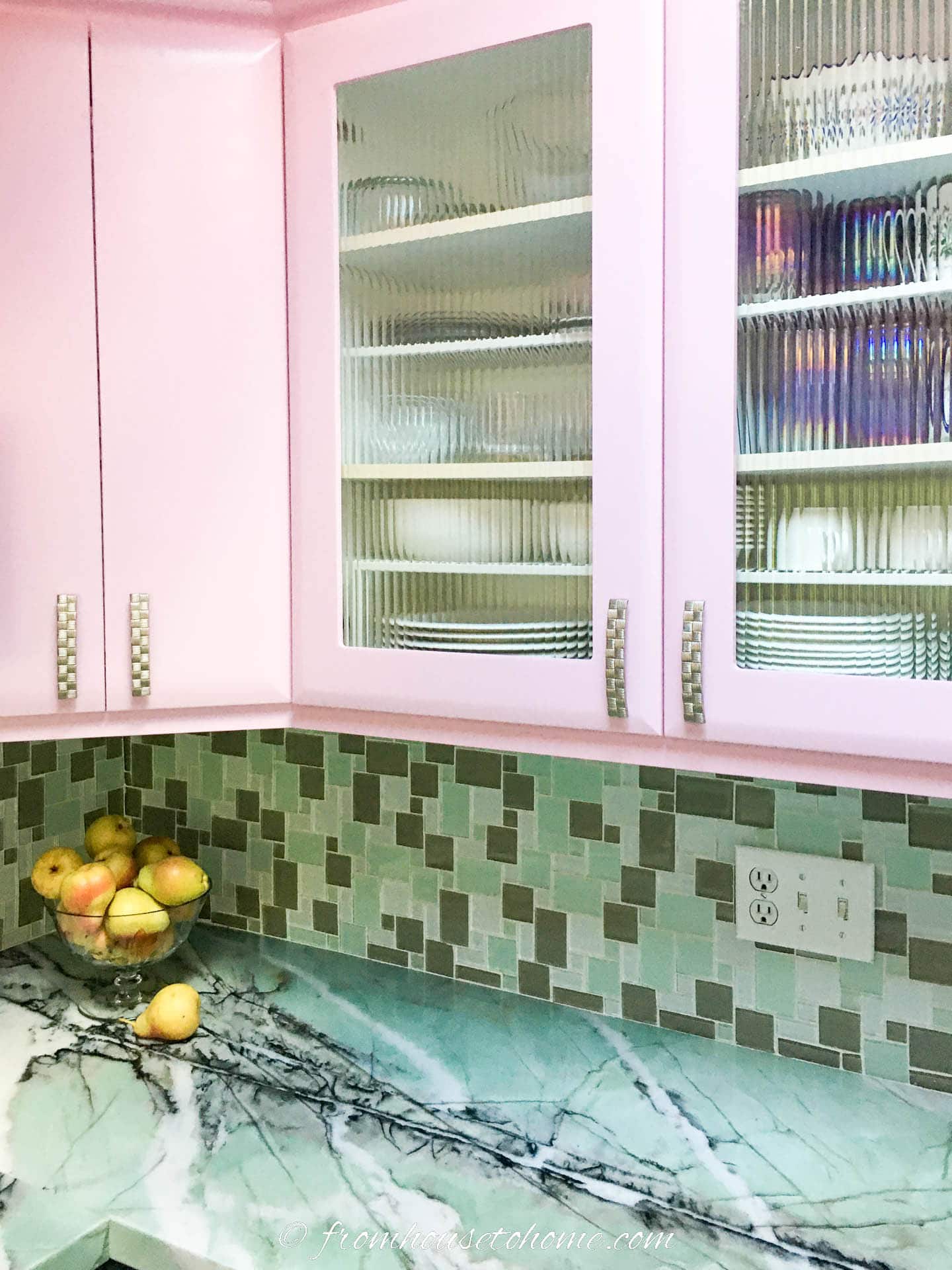 Close up of the light pink kitchen cabinets with the teal glass mosaic backsplash and countertop