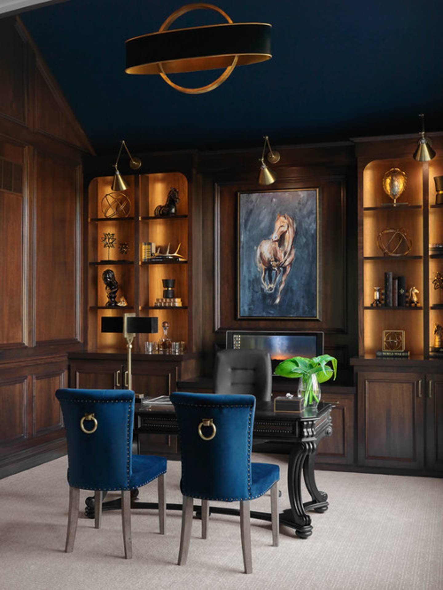 A traditional wood paneled office with blue chairs, painting and ceiling.