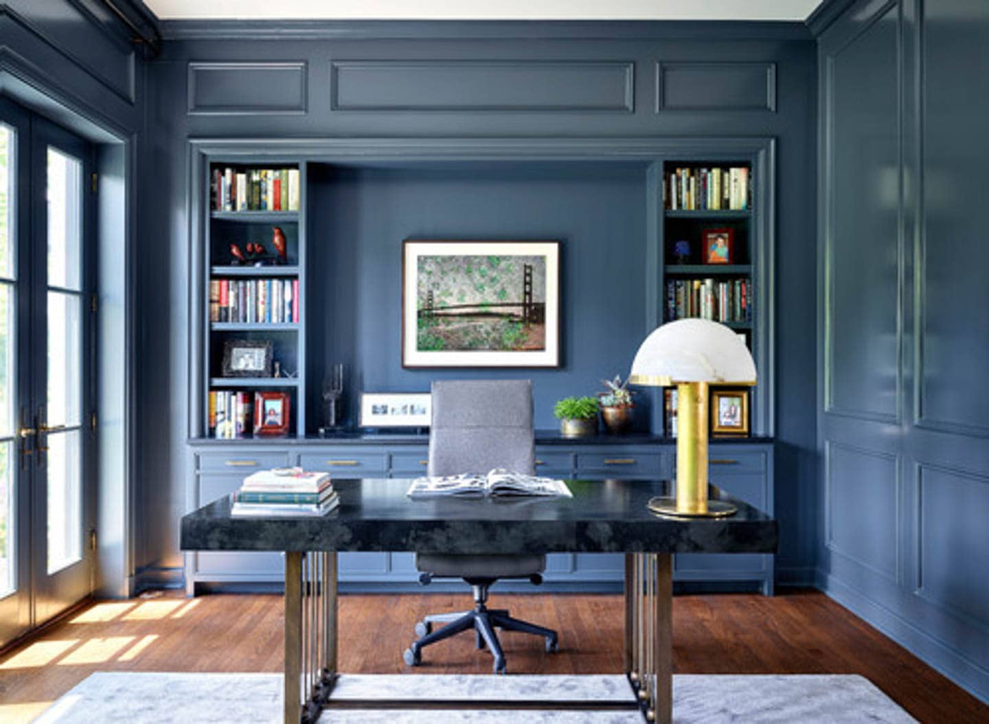 Home office with dark blue walls and shelves and a black desk