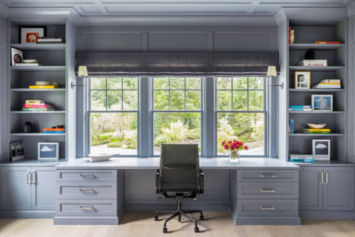 Grey blue shelves with a built-in desk facing a large window