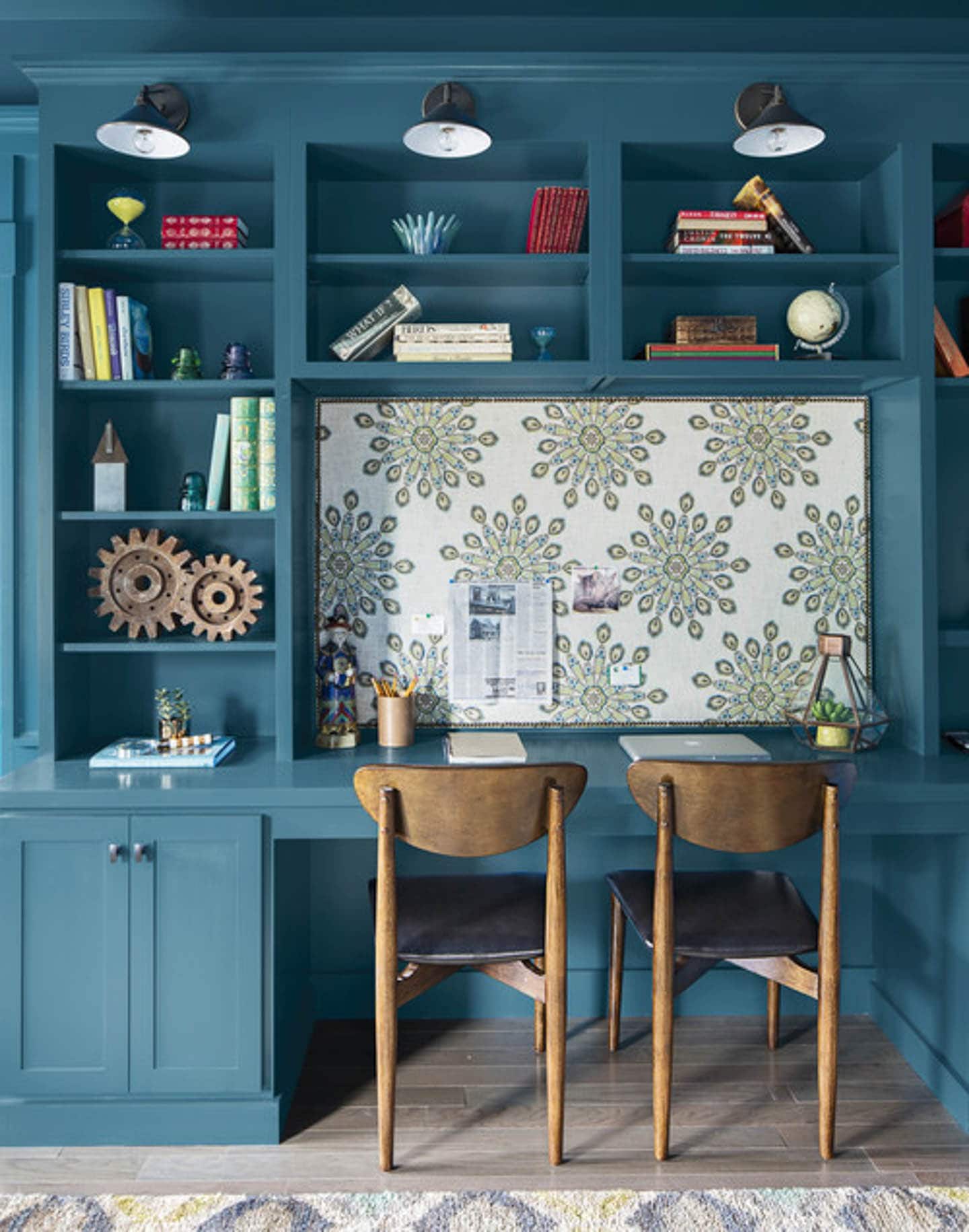 Teal shelves with a built-in desk with an upholstered bulletin board above it