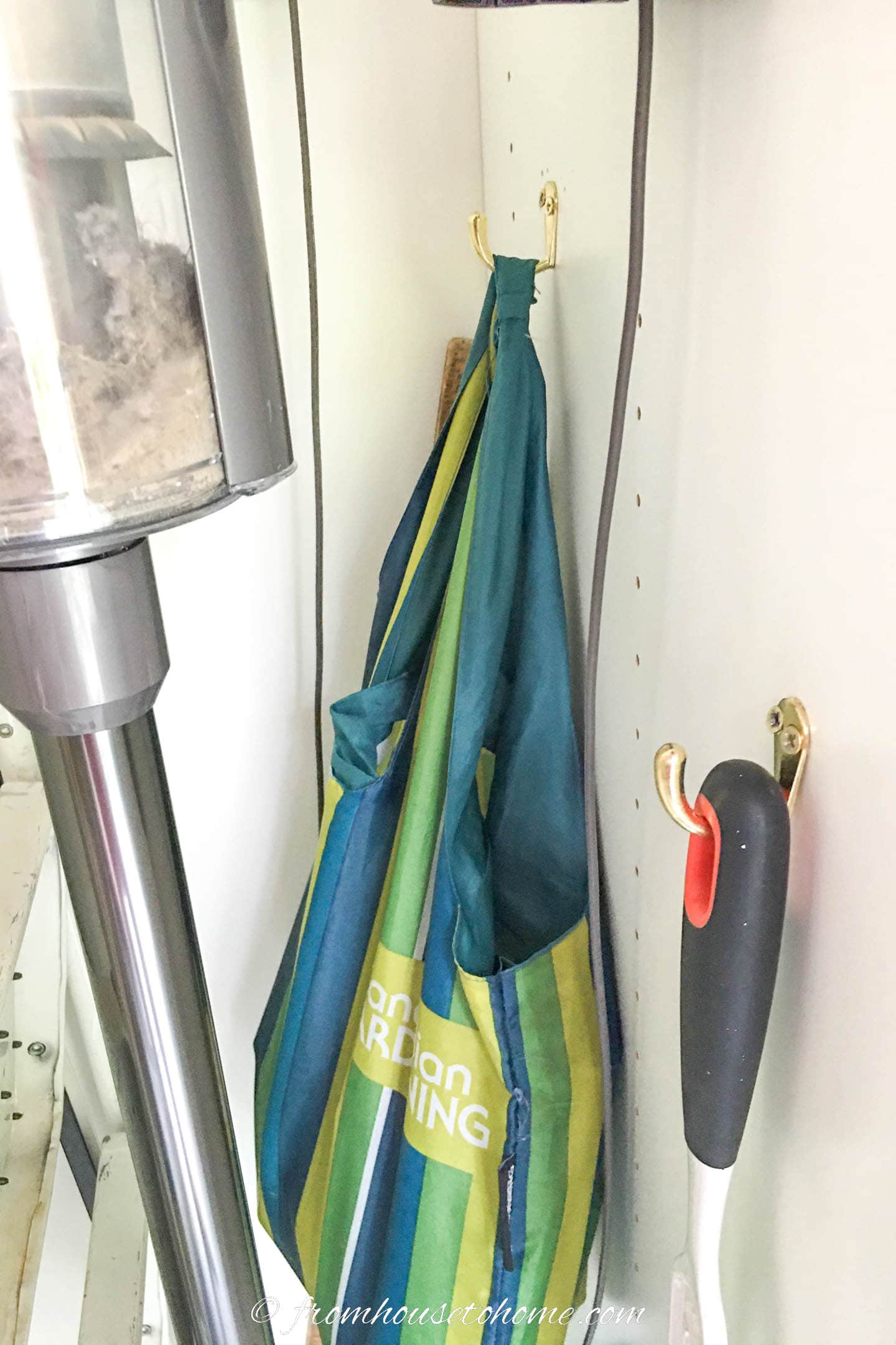 A bag storing vacuum accessories hung in a kitchen pantry