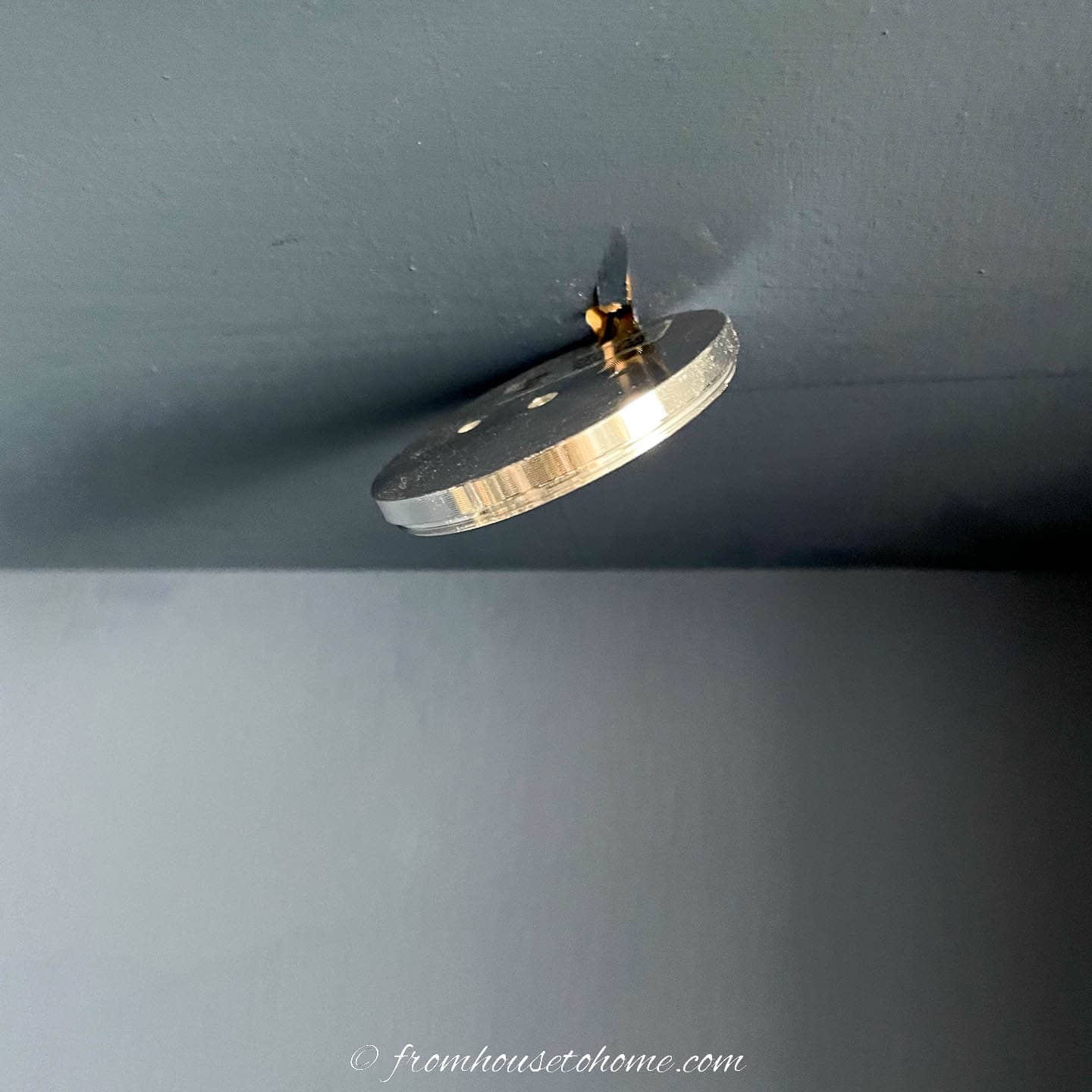 Puck light cord being fed through a hole in a shelf
