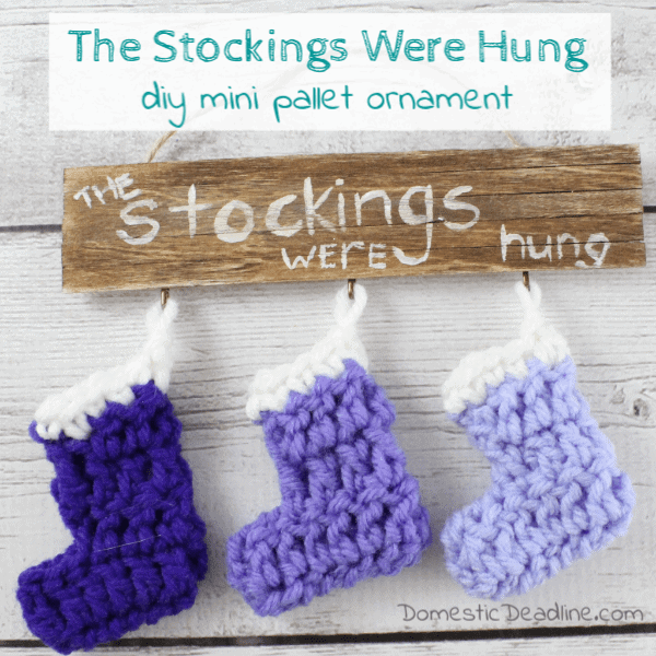 mini crocheted stockings on a wood pallet sign