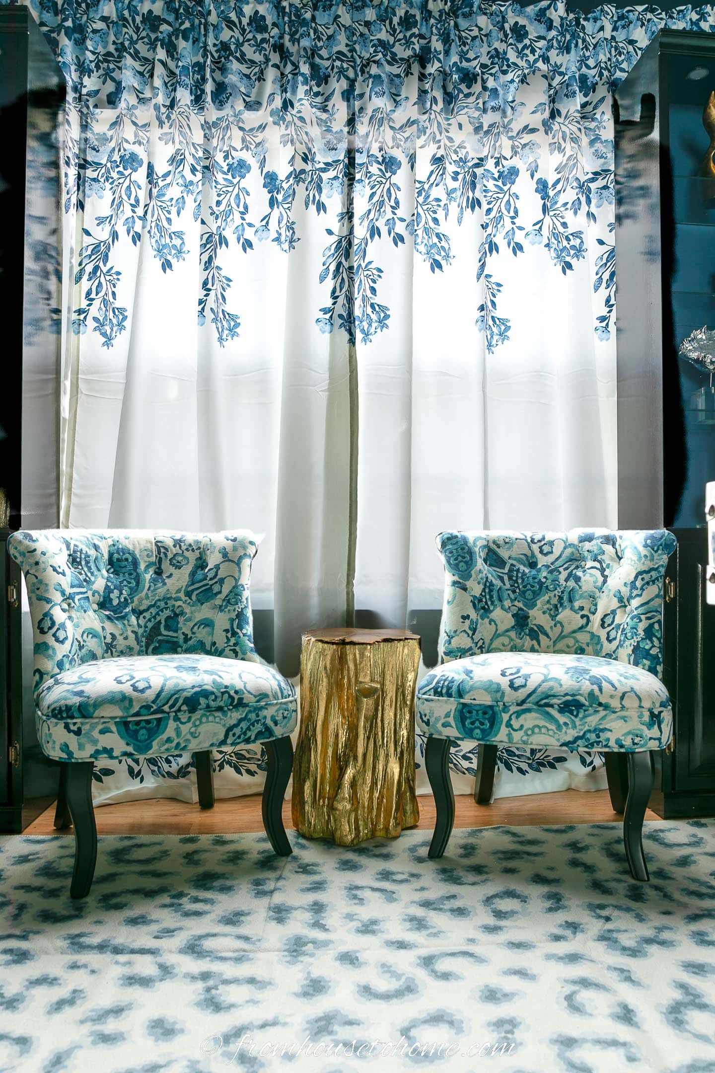 Two small chairs and a table in front of blue and white curtains