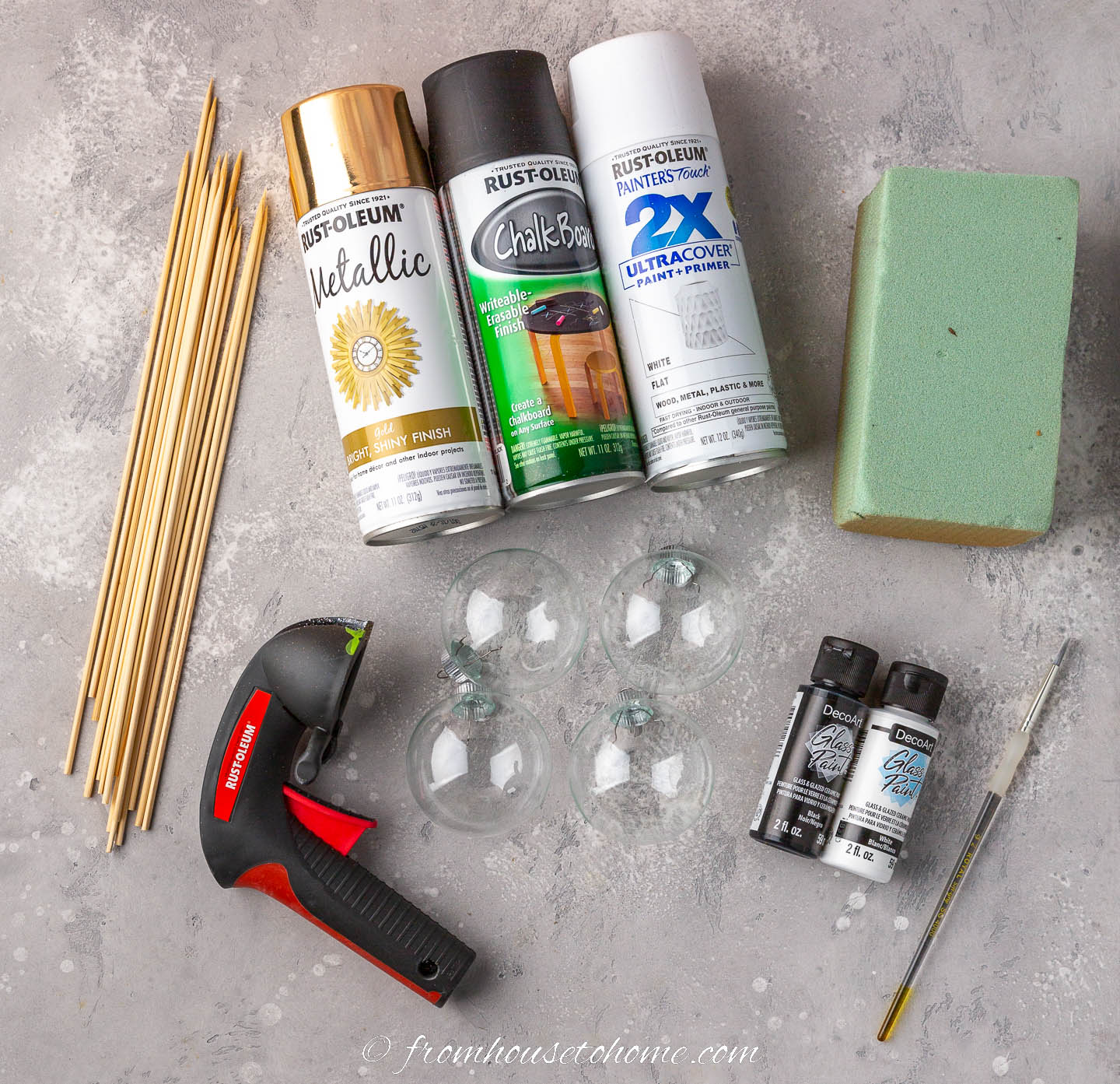 Materials and equipment to make DIY black and white polka dot ornaments - spray paint, floral foam, skewers, paint spray trigger, clear ornaments, glass paint and a small paint brush
