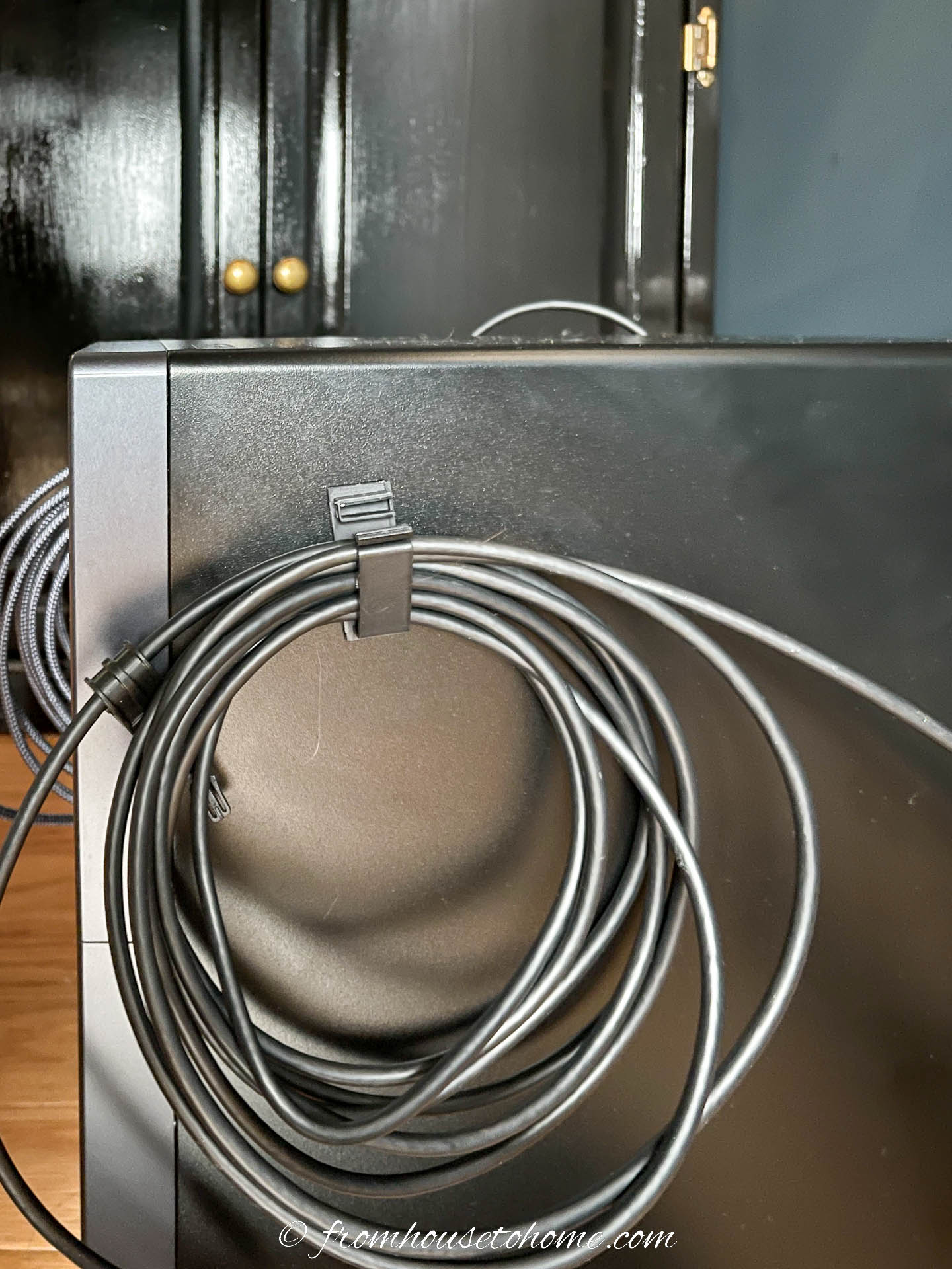 An adhesive computer clip holding a coil of wire attached to the side of a PC