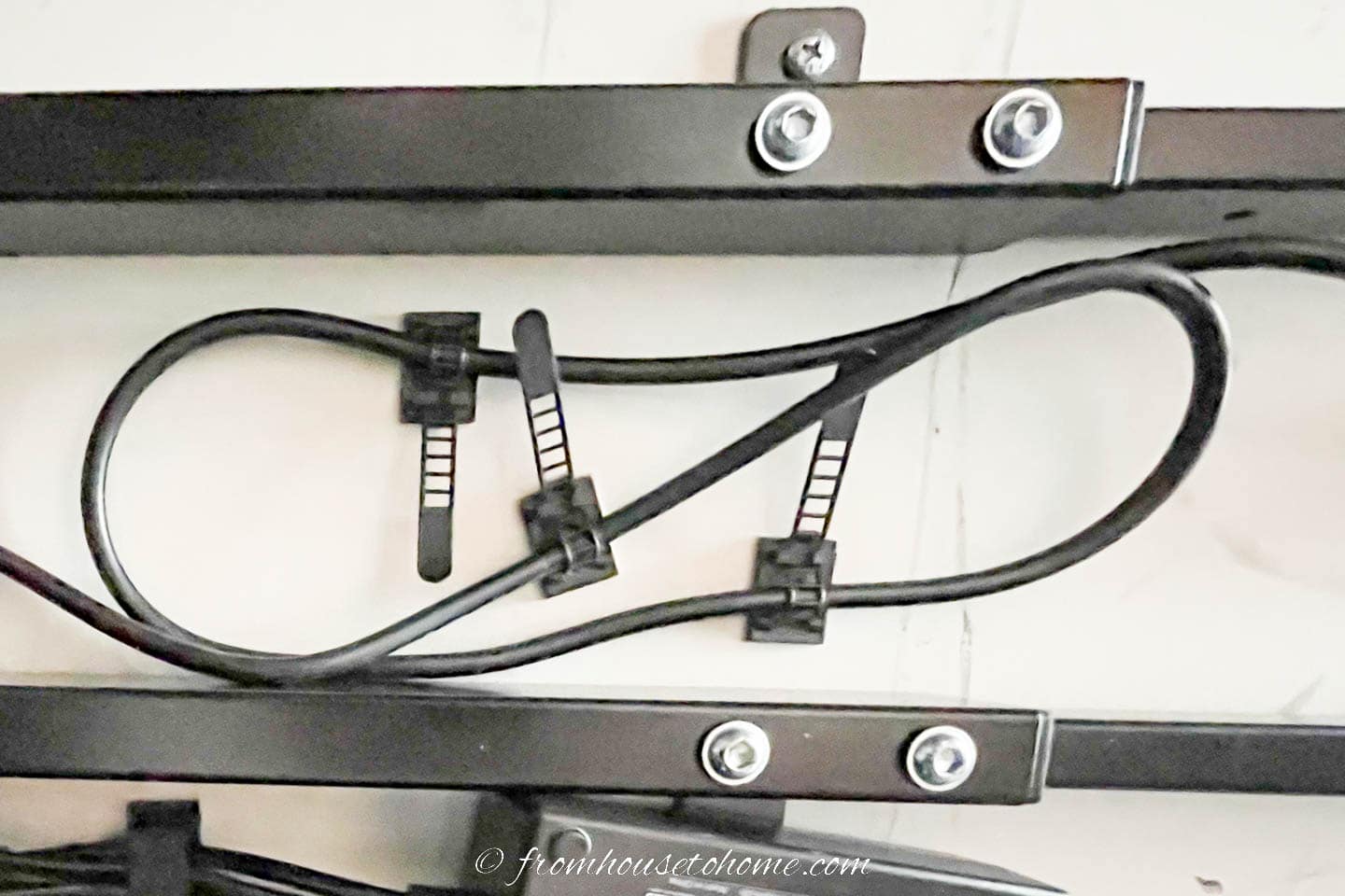 Individual cable ties holding a cord up underneath a desk