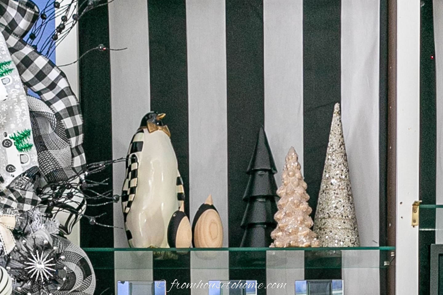 A set of penguins and black and white mini evergreen trees on a bookshelf