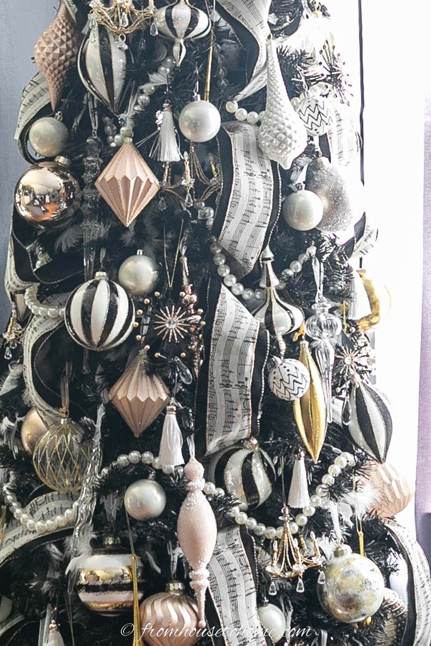 Black, white and gold ornaments on a black Christmas tree