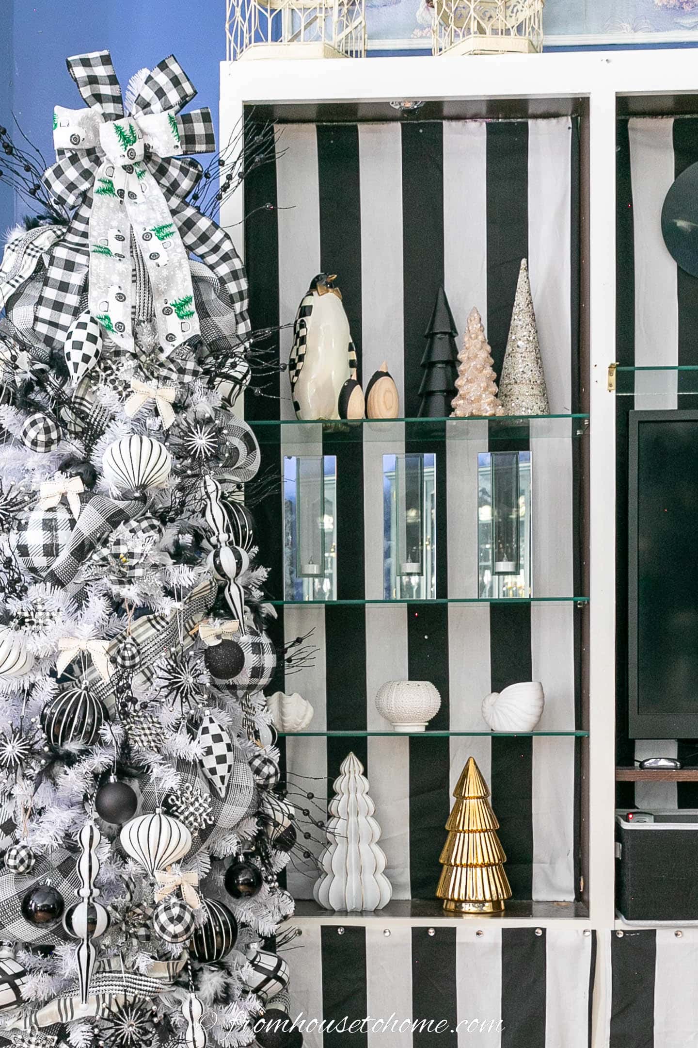 Black and white plaid Christmas tree beside bookshelves lined with black and white striped fabric