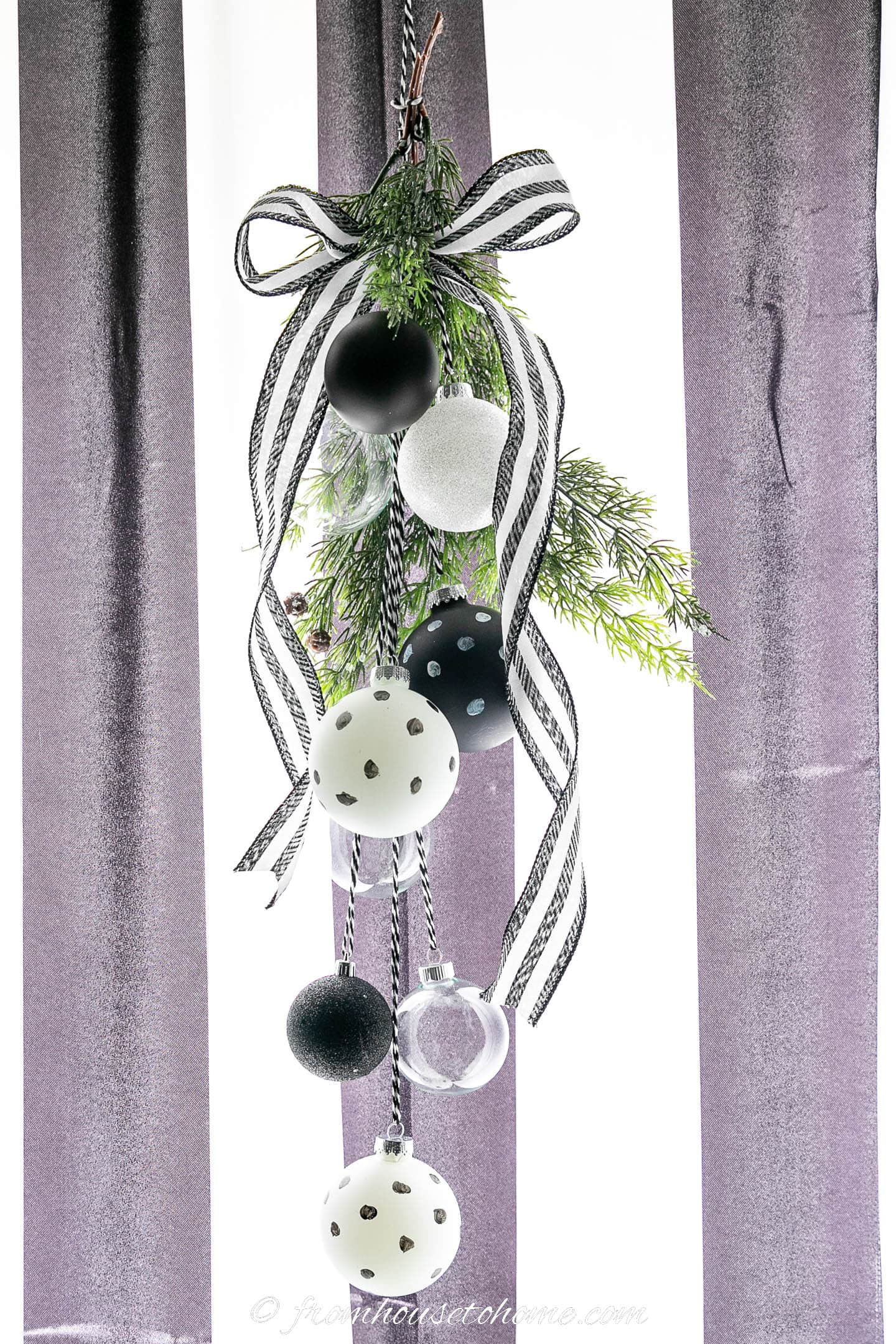 DIY door swag made with black and white ribbon, faux evergreens and black and white ornaments