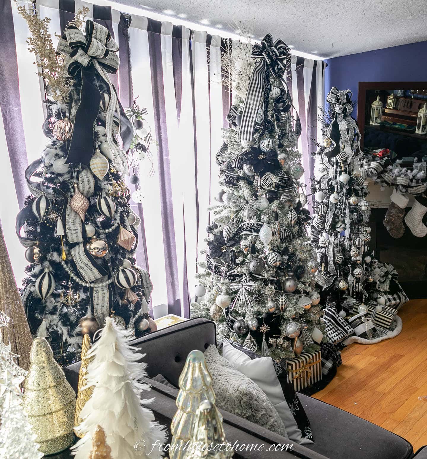 Three black and white Christmas trees in front of black and white striped curtains