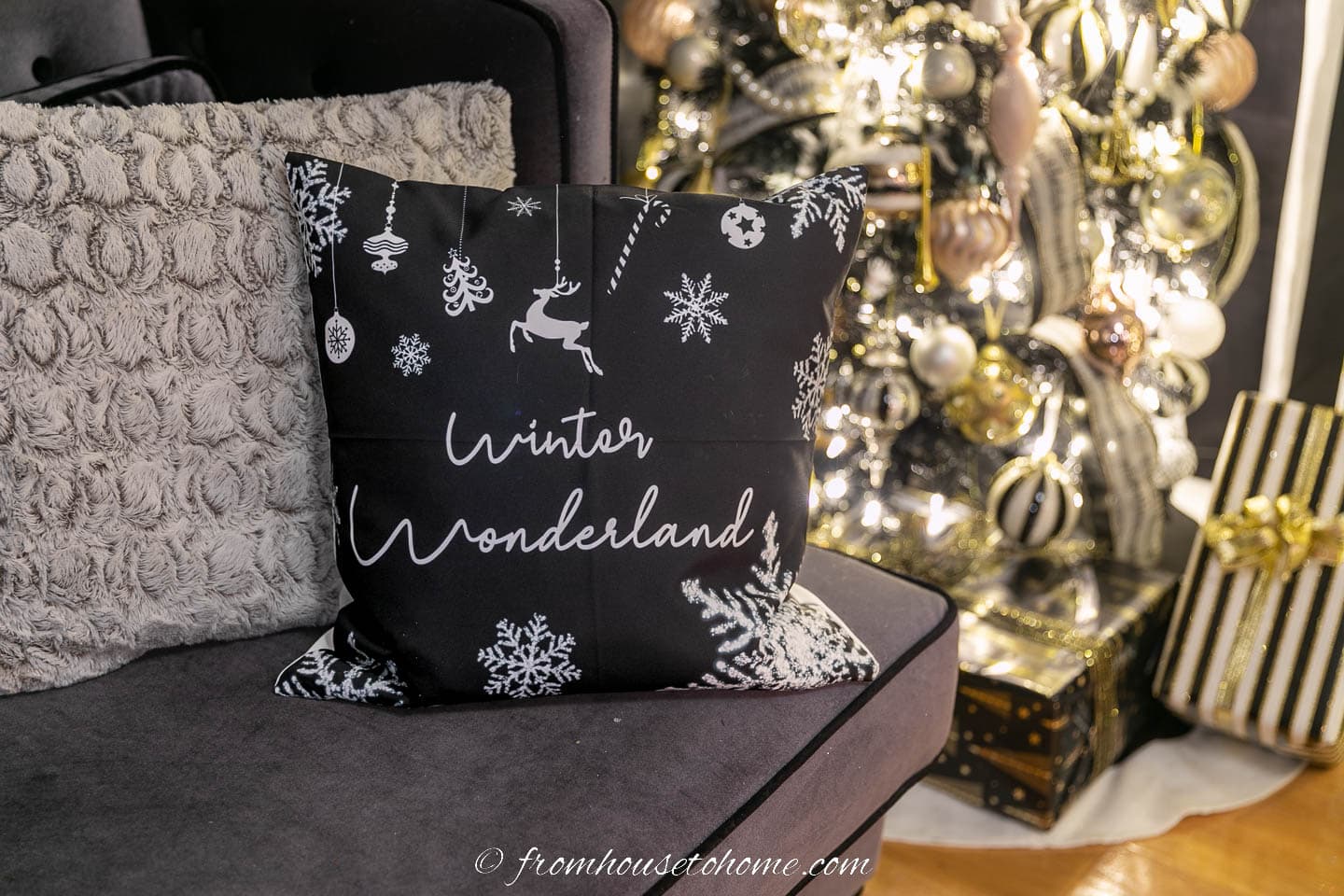 Black "Winter Wonderland" cushion on a sofa in front of a Christmas tree
