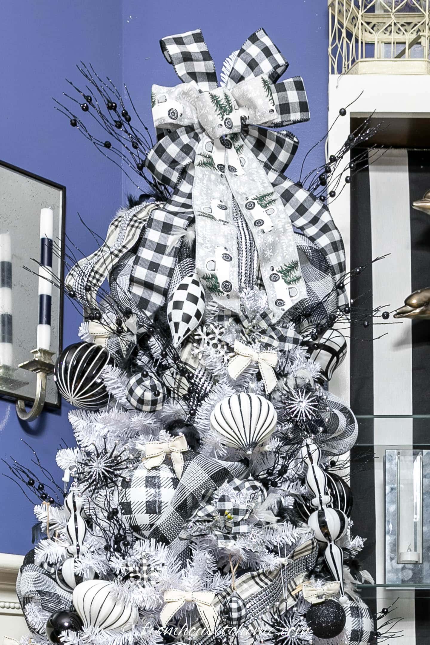 Black and white plaid tree topper with black spray picks on top of a buffalo check tree