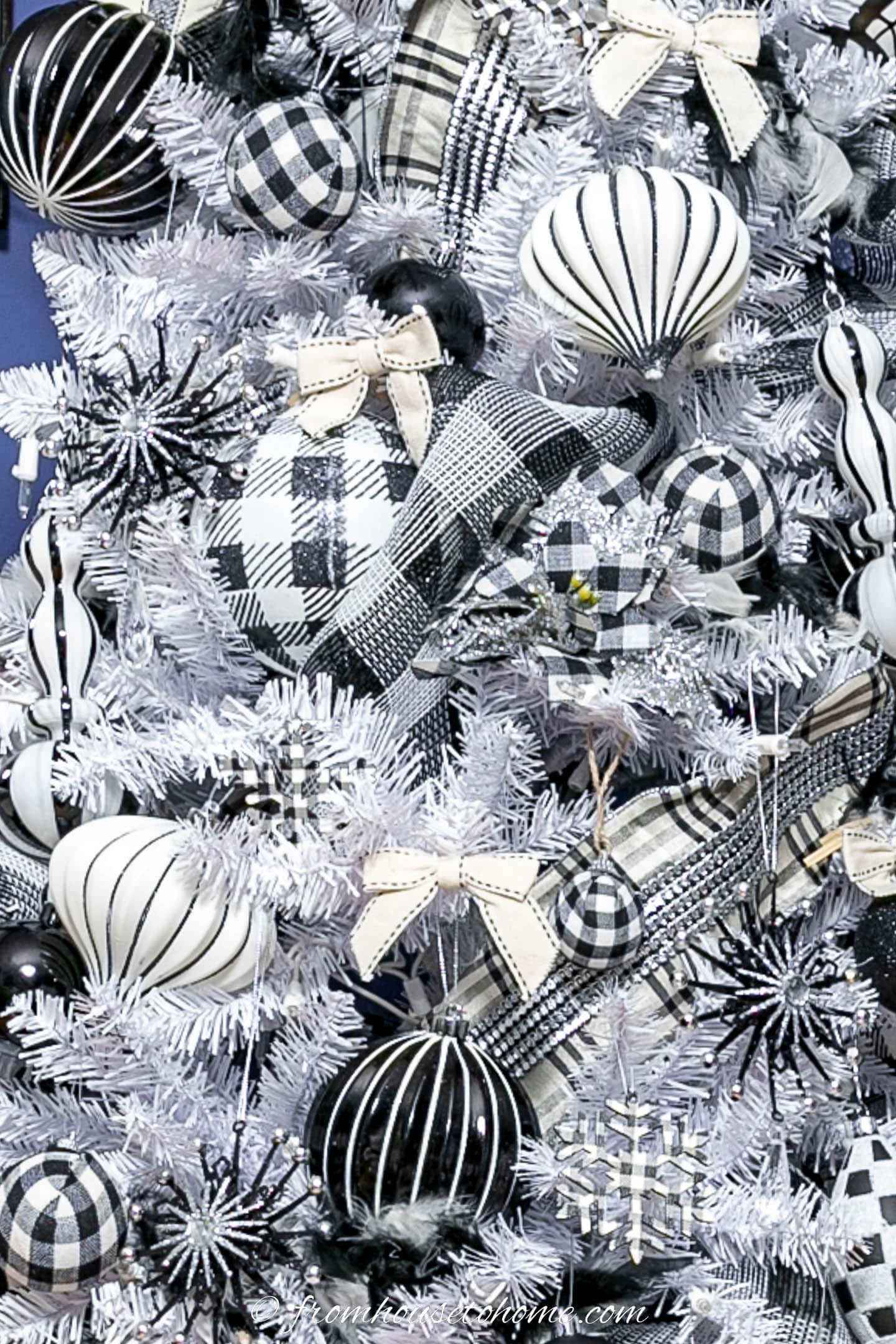 Close up of a white tree with black and white ornaments and white bows