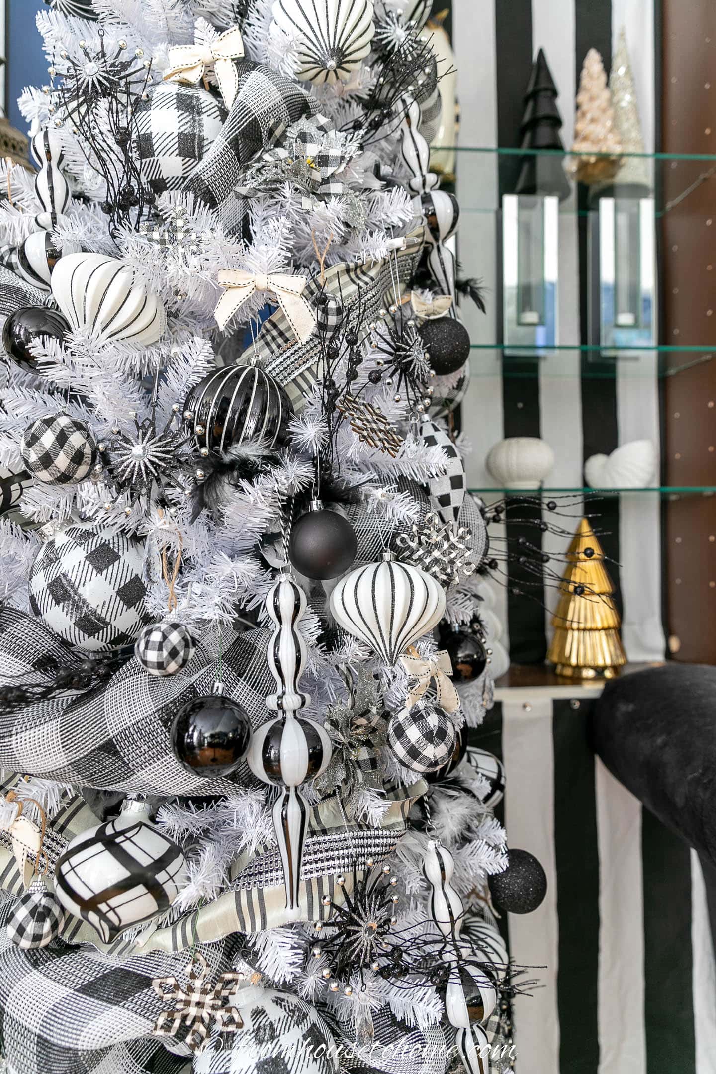 Close up of a black and white plaid Christmas tree in front of shelves with black and white stripes