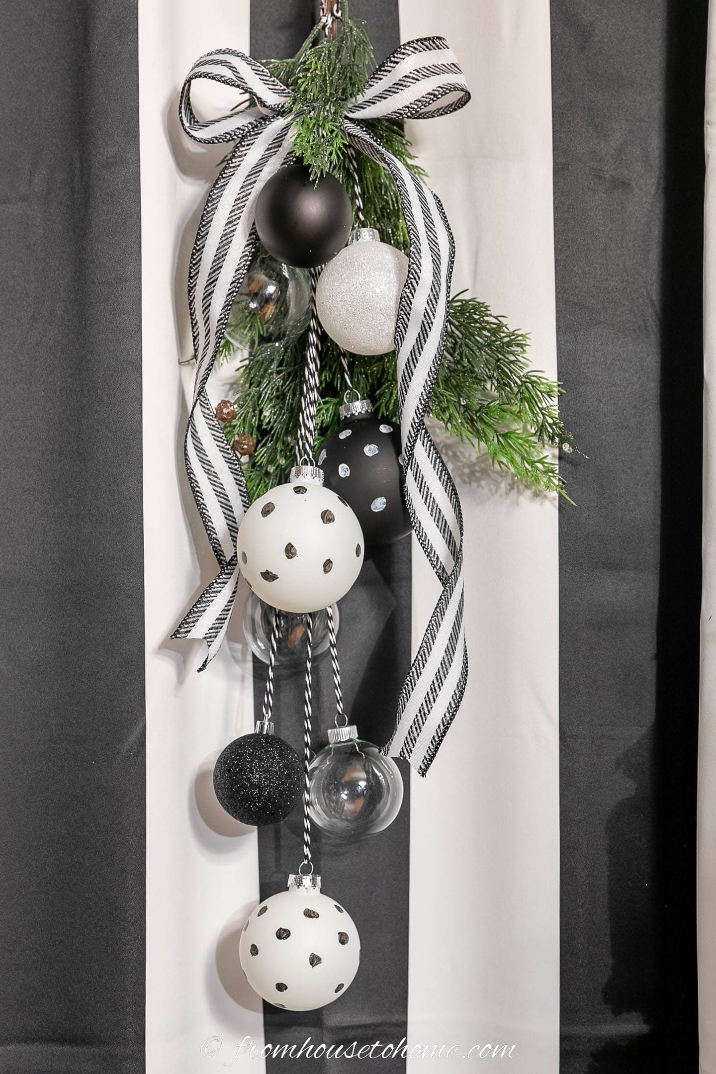 The finished DIY black and white Christmas swag hung in front of a window with black and white curtains