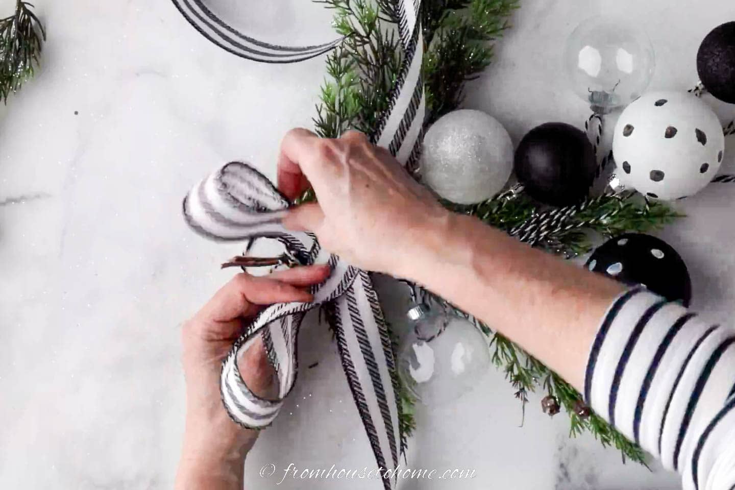Black and white ribbon being tied in a bow on a Christmas swag