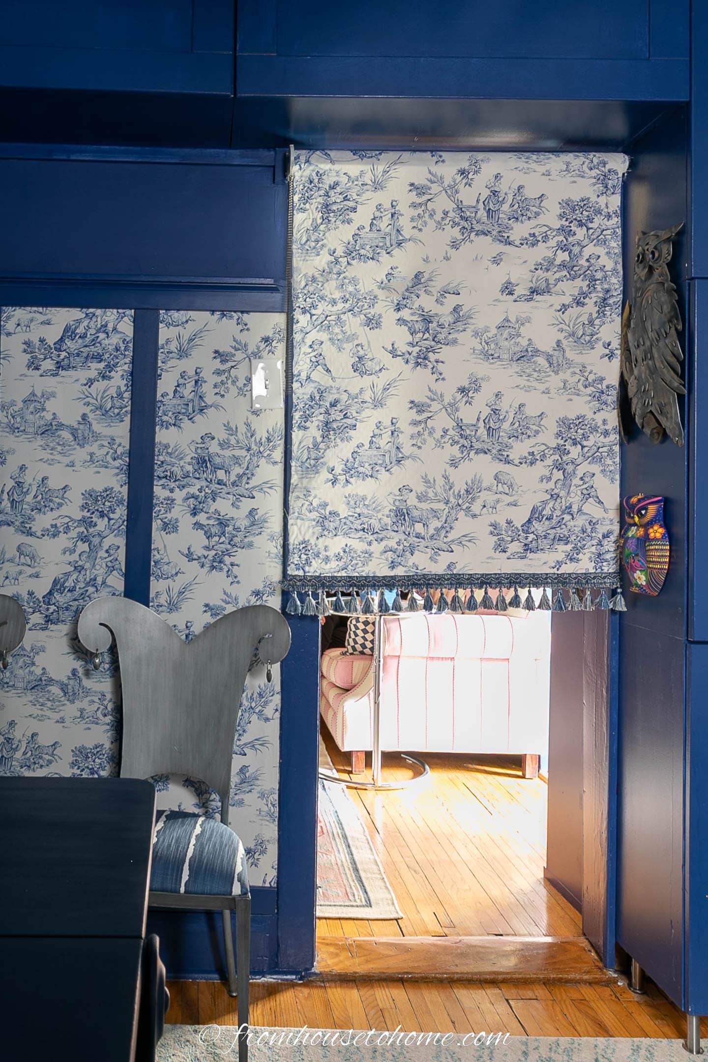 The home office door partly covered by a blue and white toile roller blind