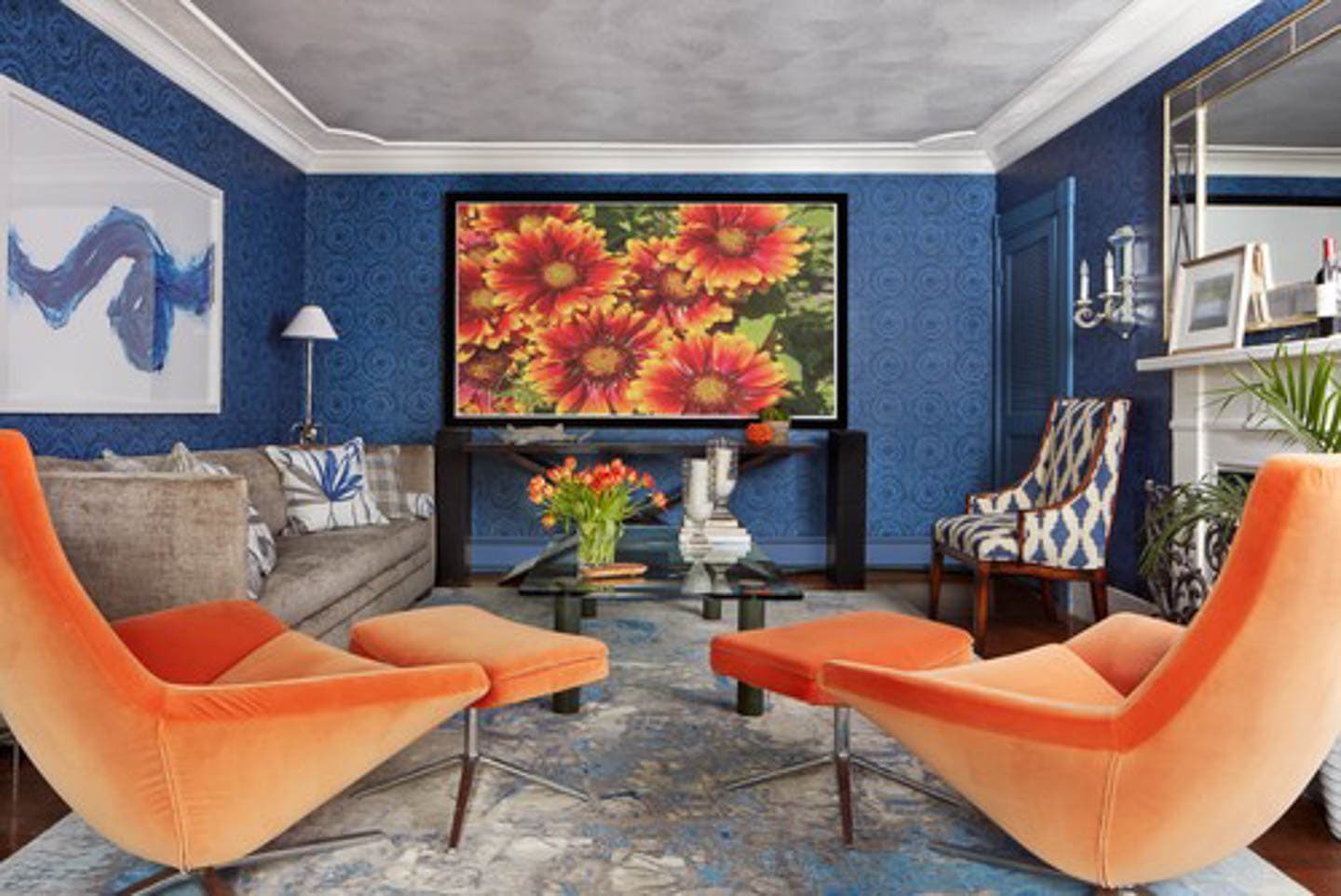 Blue living room with gray sofa, orange chairs and a large silver area rug