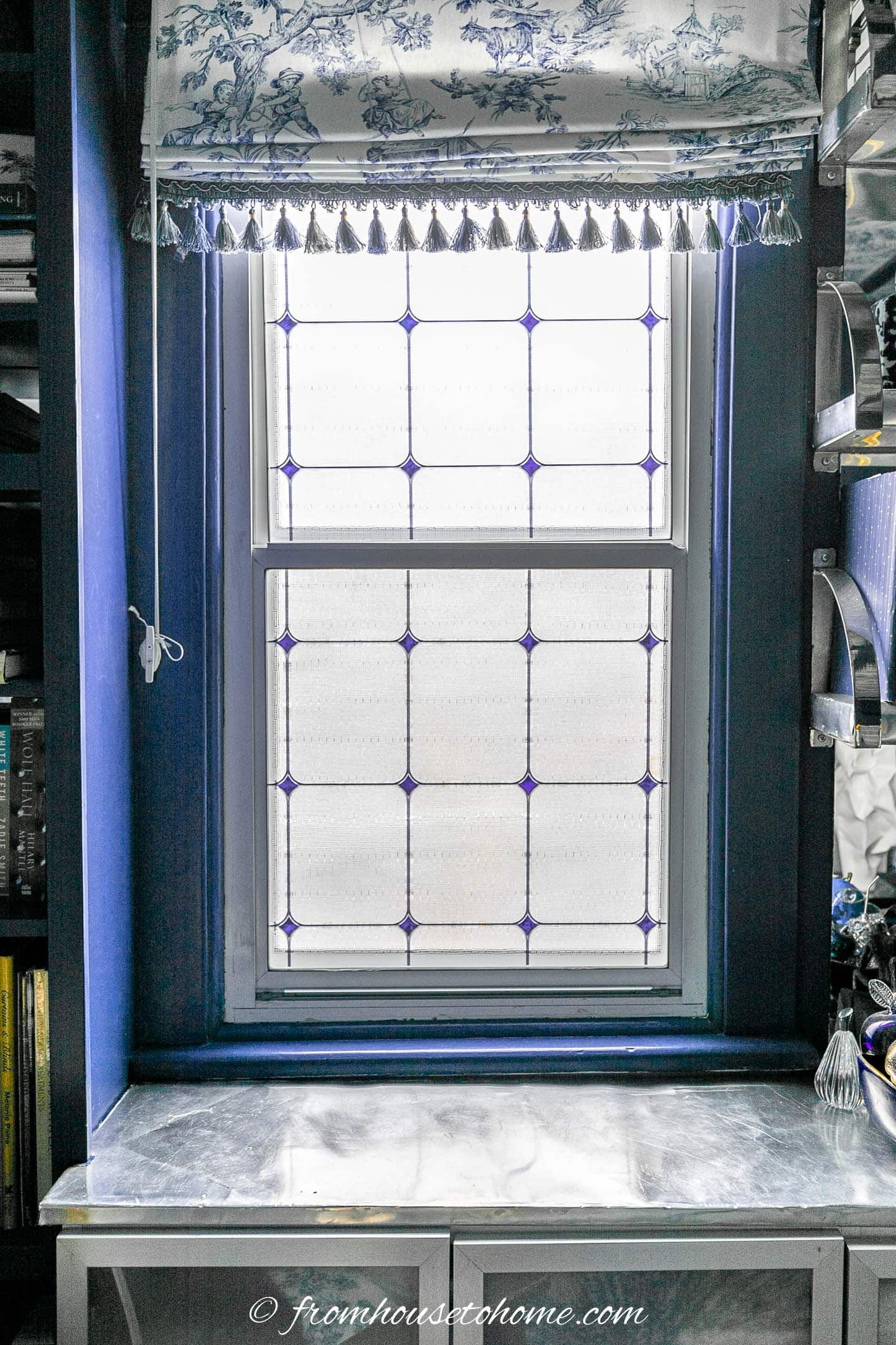 window with frosted window film and blue and white roman shade