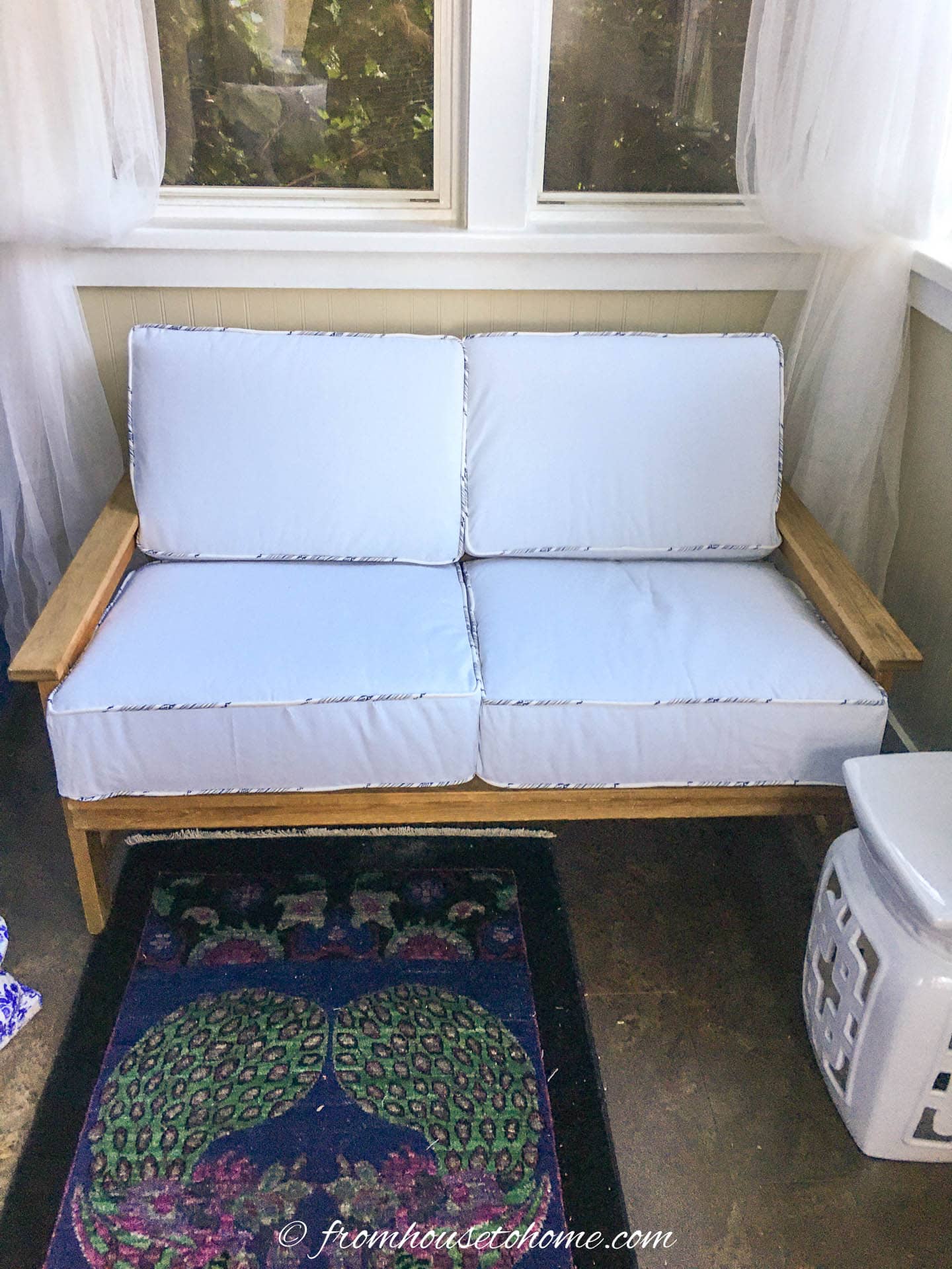 pine loveseat with white cushions in a front porch